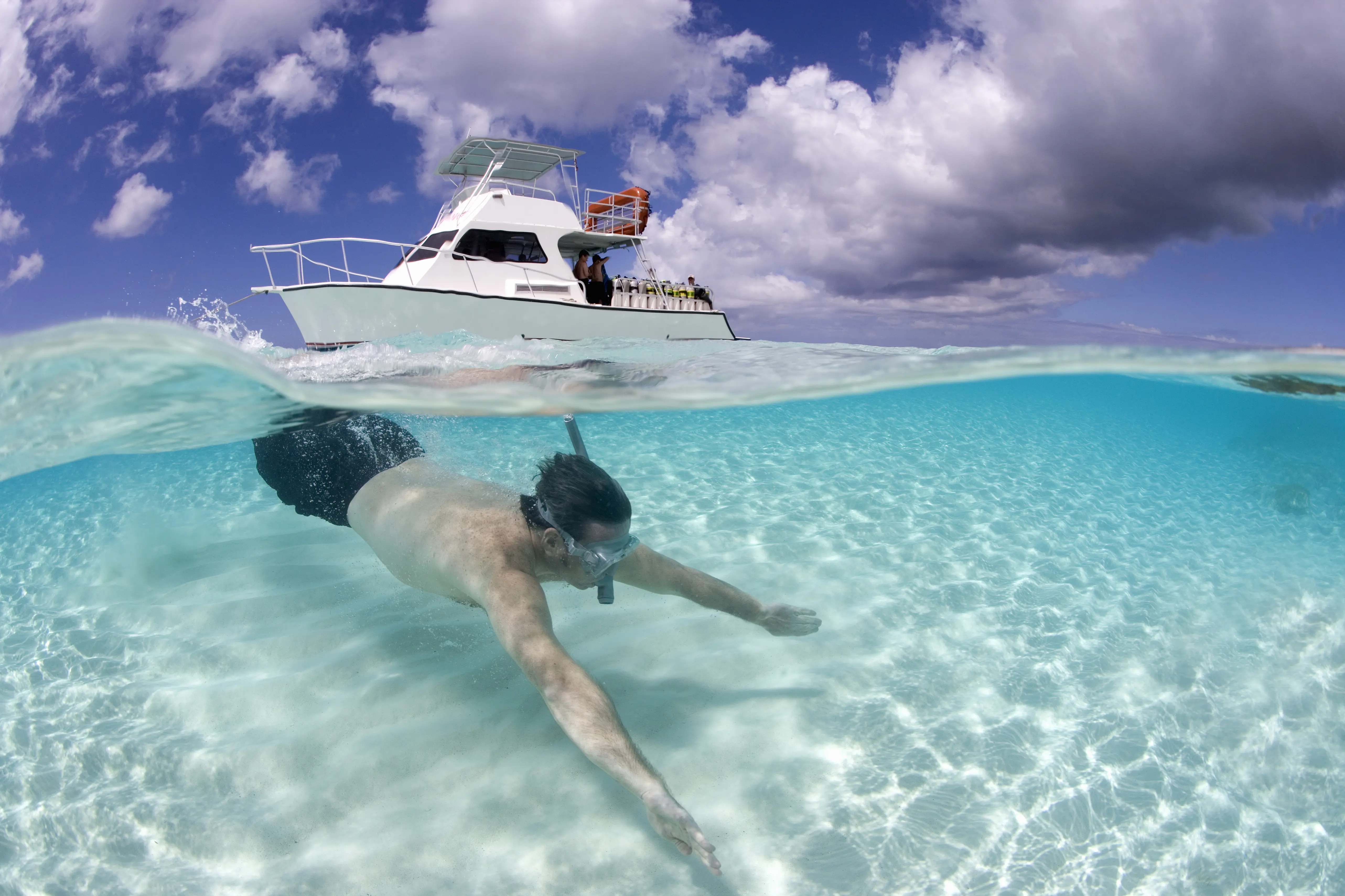 Image of a man snorkeling at Turks and Caicos, with a boat above him.