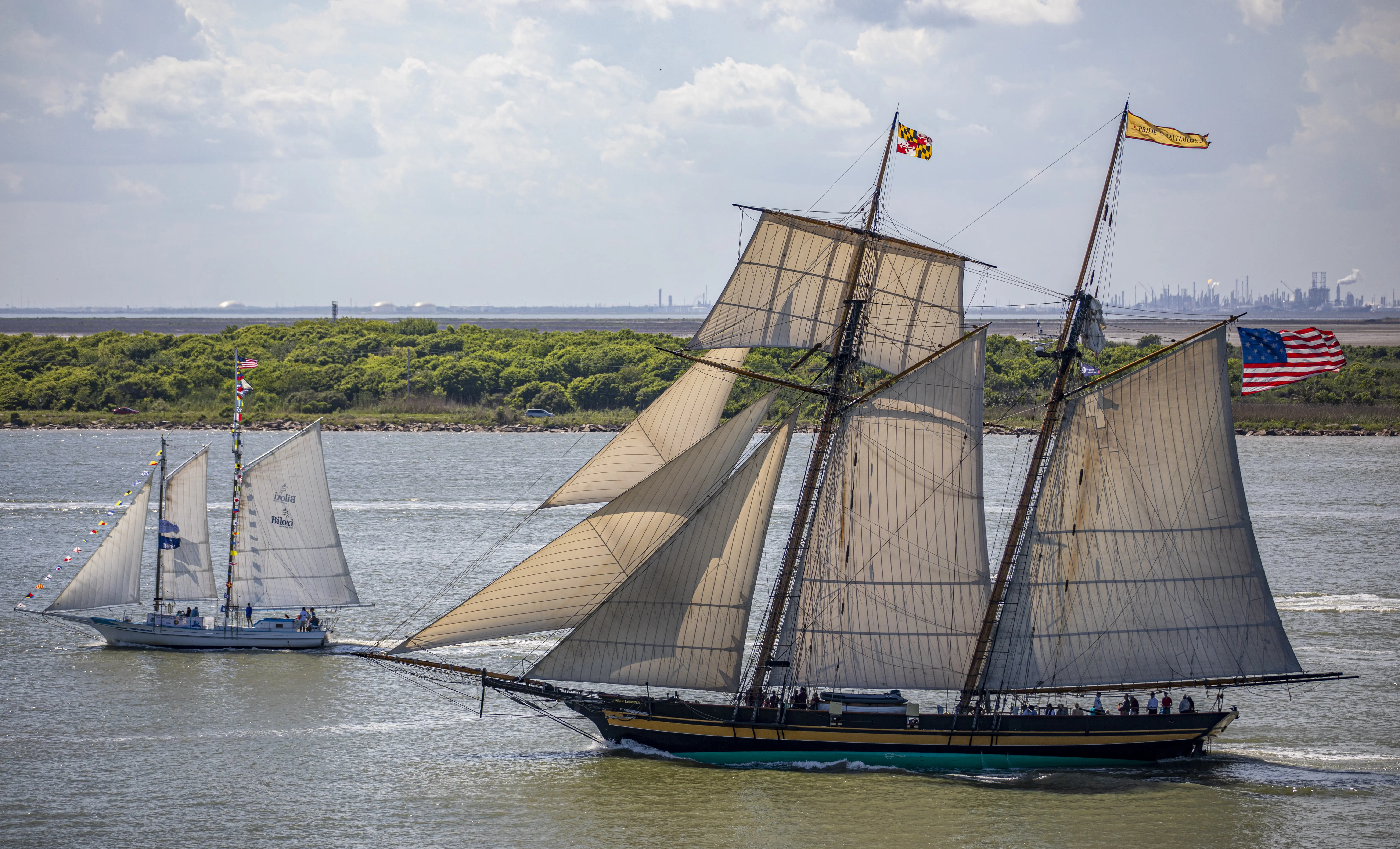 Image of a square-topsail schooner and reconstruction of an early 19th-century Baltimore Clipper, and two-masted, gaff-rigged, Biloxi Oyster Schooner Glenn L. Swetman, transit Galveston Channel during Tall Ships Challenge Galveston 2023.