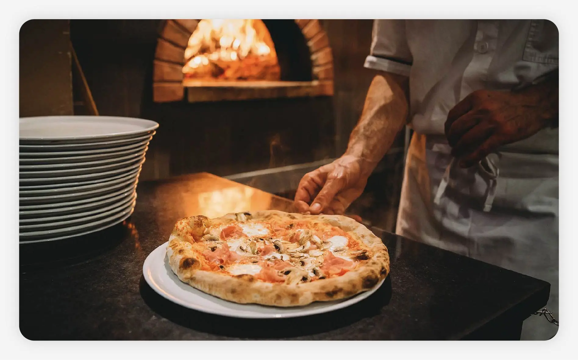 A chef taking a pizza out of the oven