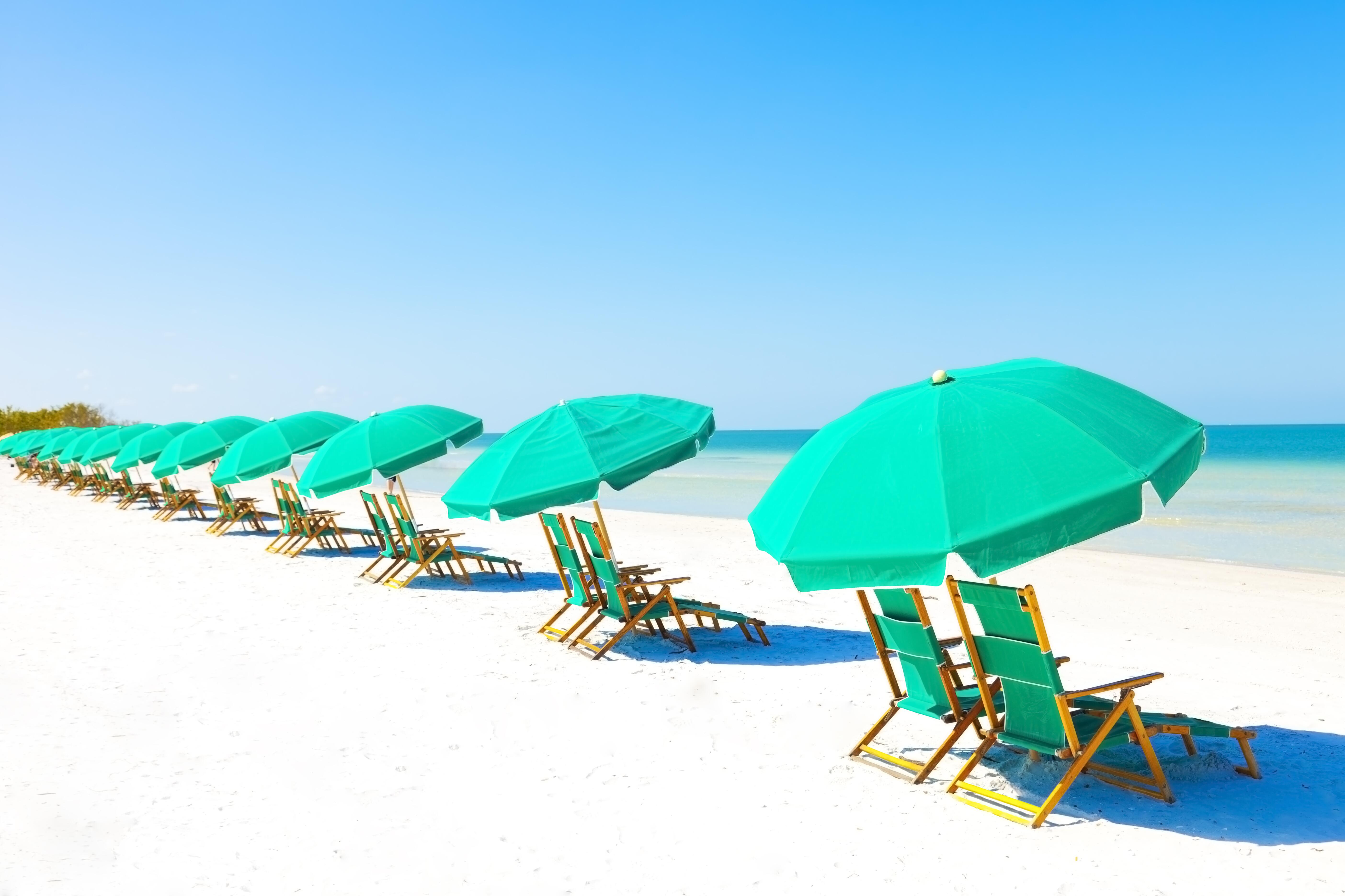 Green lounge chairs and umbrellas at the beach