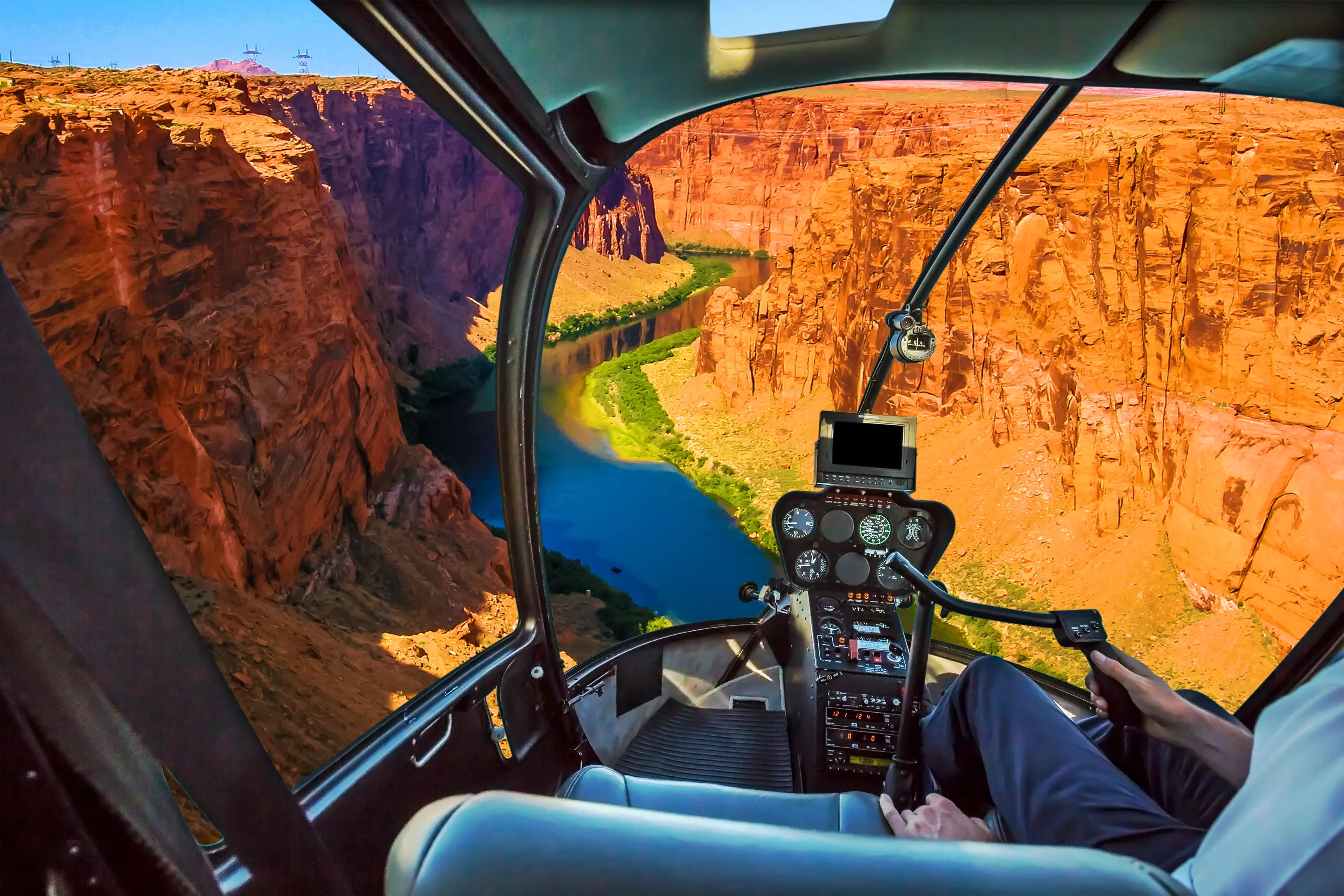 Helicopter cockpit with pilot arm and control console inside the cabin looking down on the Grand Canyon Lake Powell