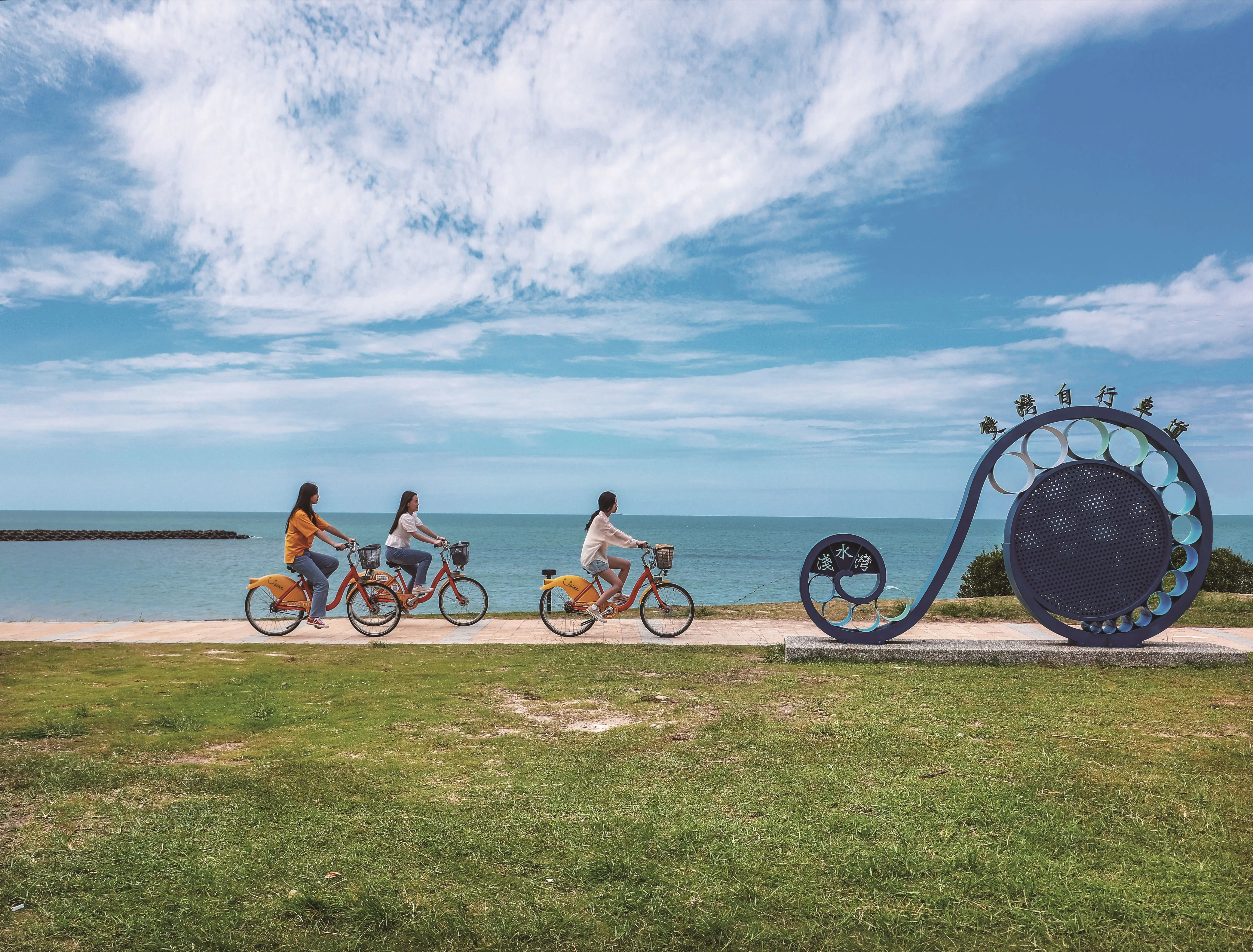 Image of people riding bicycles past a public art sculpture in Taiwan.
