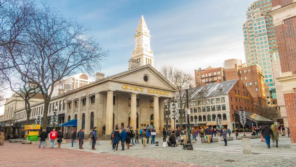 Outdoor view of Quincy Market in Boston during the day time with people walking through.