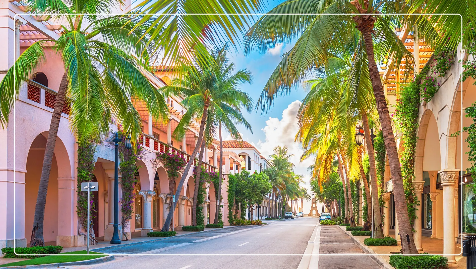 A street lined with pink buildings and palm trees in Palm Beach.