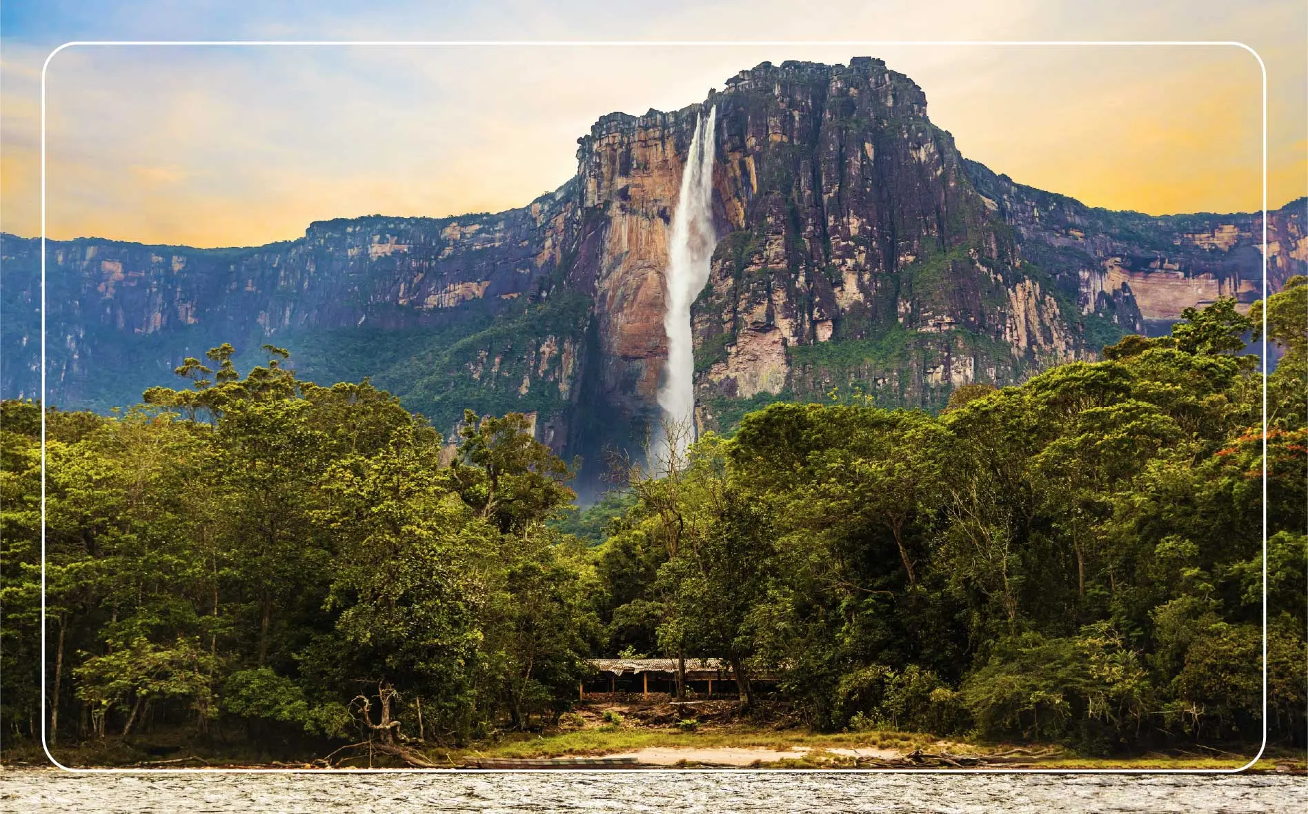 A view looking up at Angel Falls from the ground with lush greenery surrounding the falls.