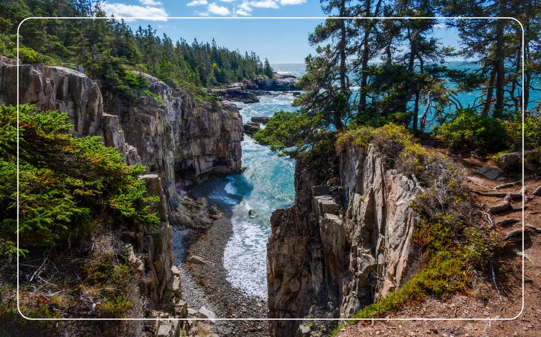 A rocky shore in the foreground leads to green mountains in the background at Acadia National Park.