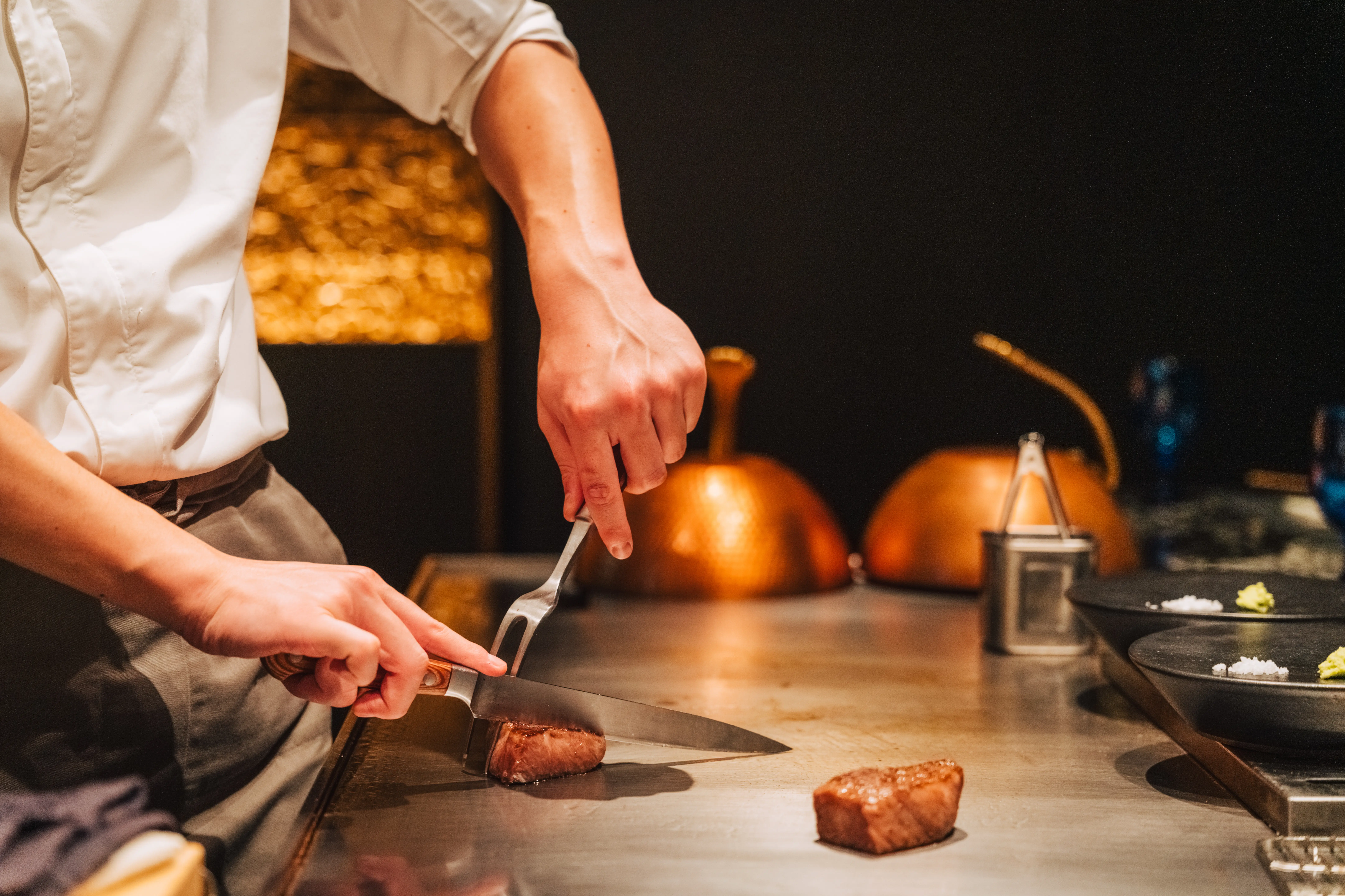 Image of a chef slicing Wagyu beef on a Japanese teppanyaki grill.