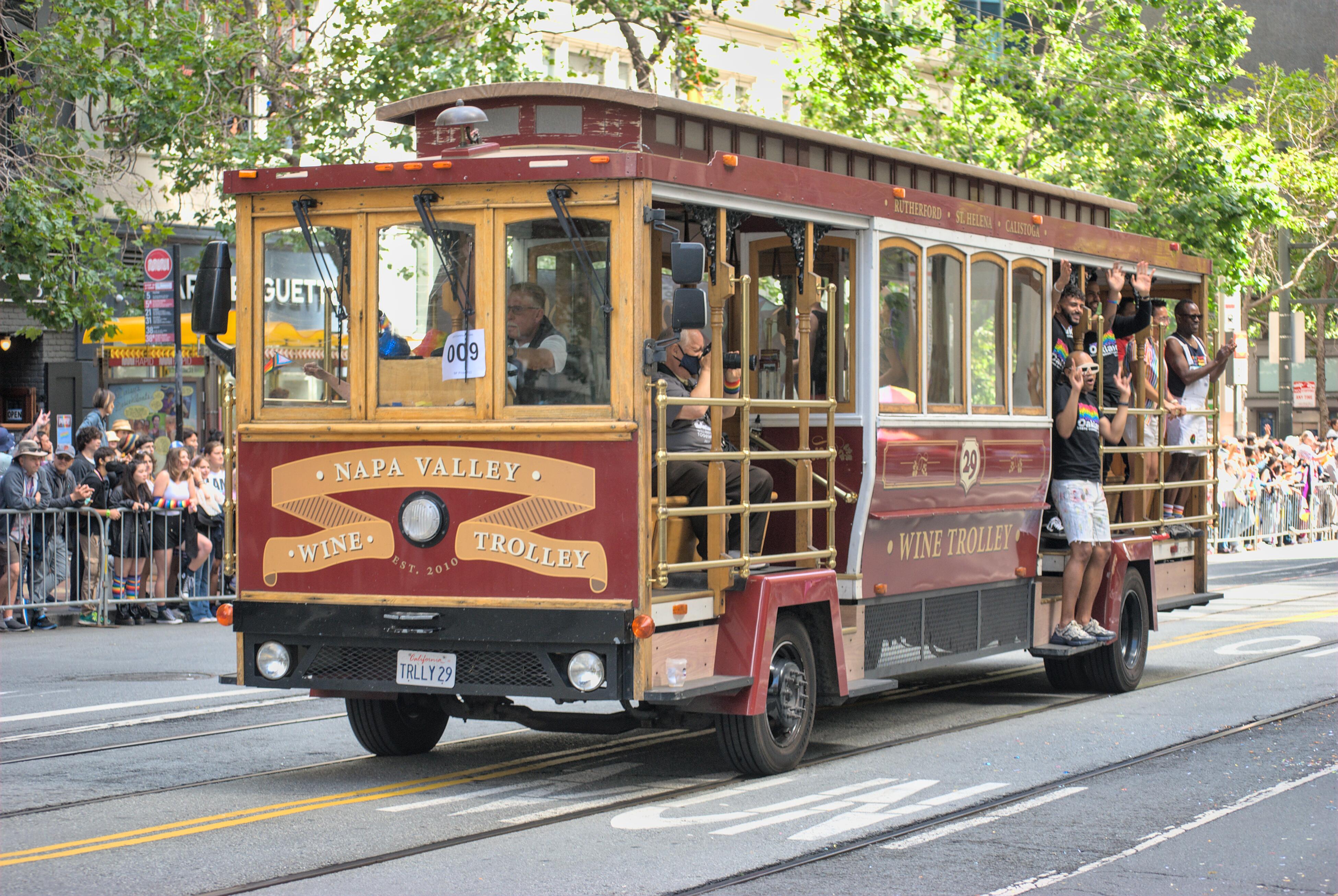 Image of a Napa Valley Wine Trolley traveling down a road for a LGBT parade event.