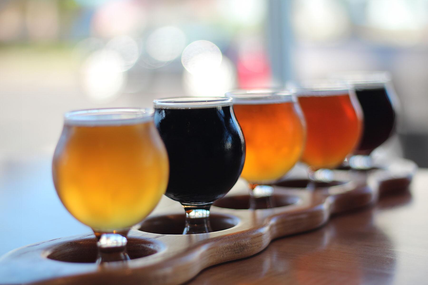 A flight of craft beers on a wooden table