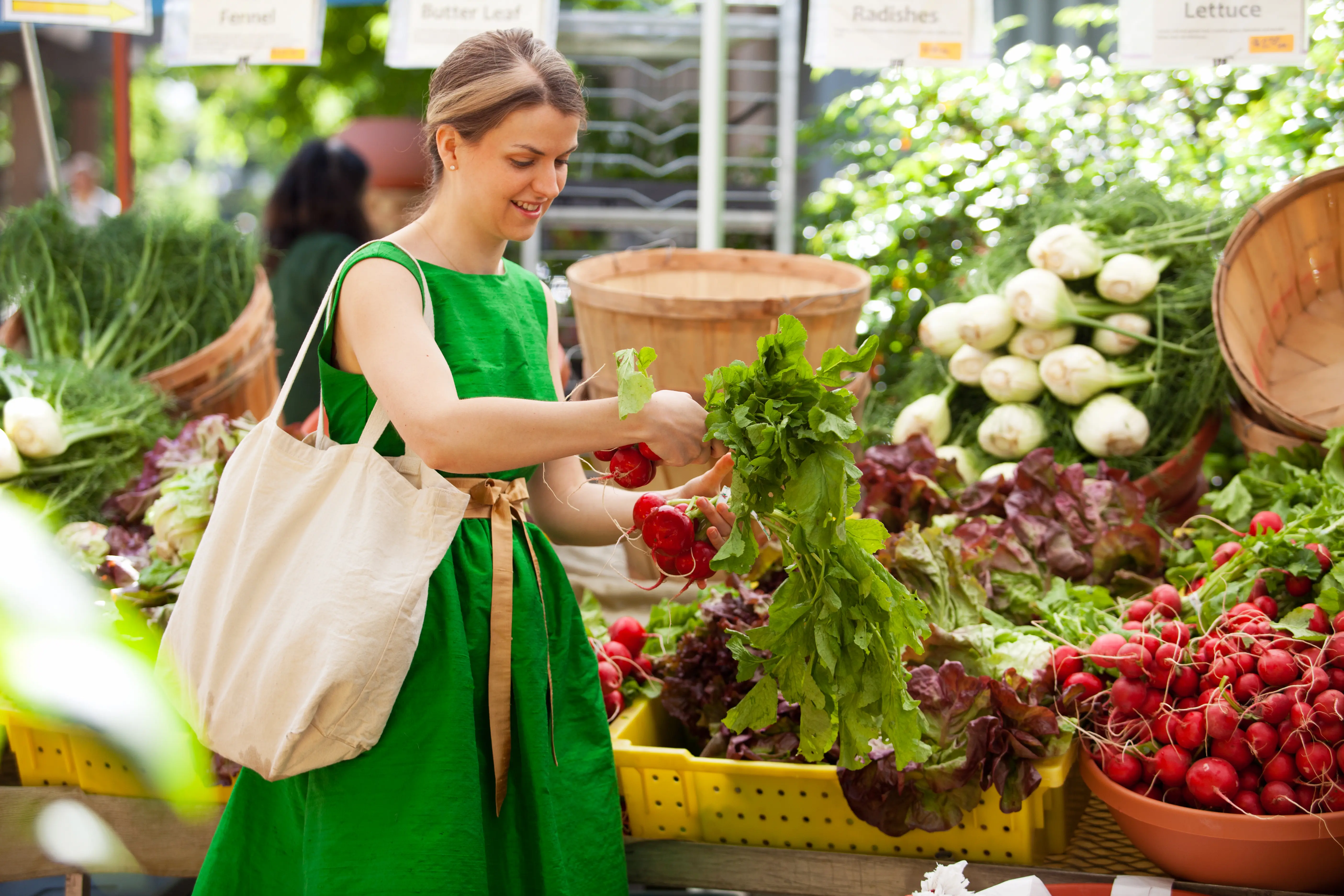 Young woman in green dress buying produce at farmer’s market