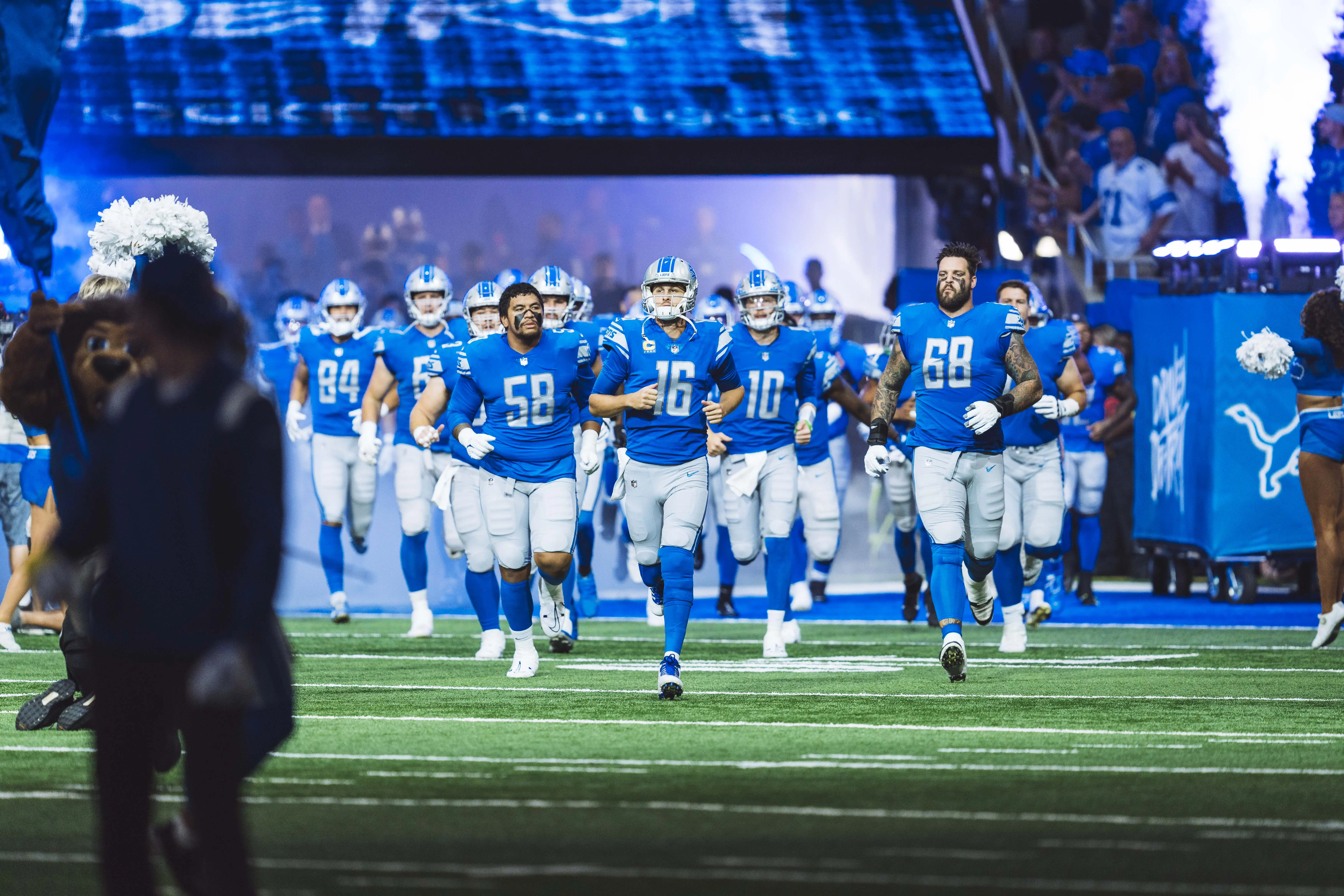 Image of the Detroit Lions football team running on field.