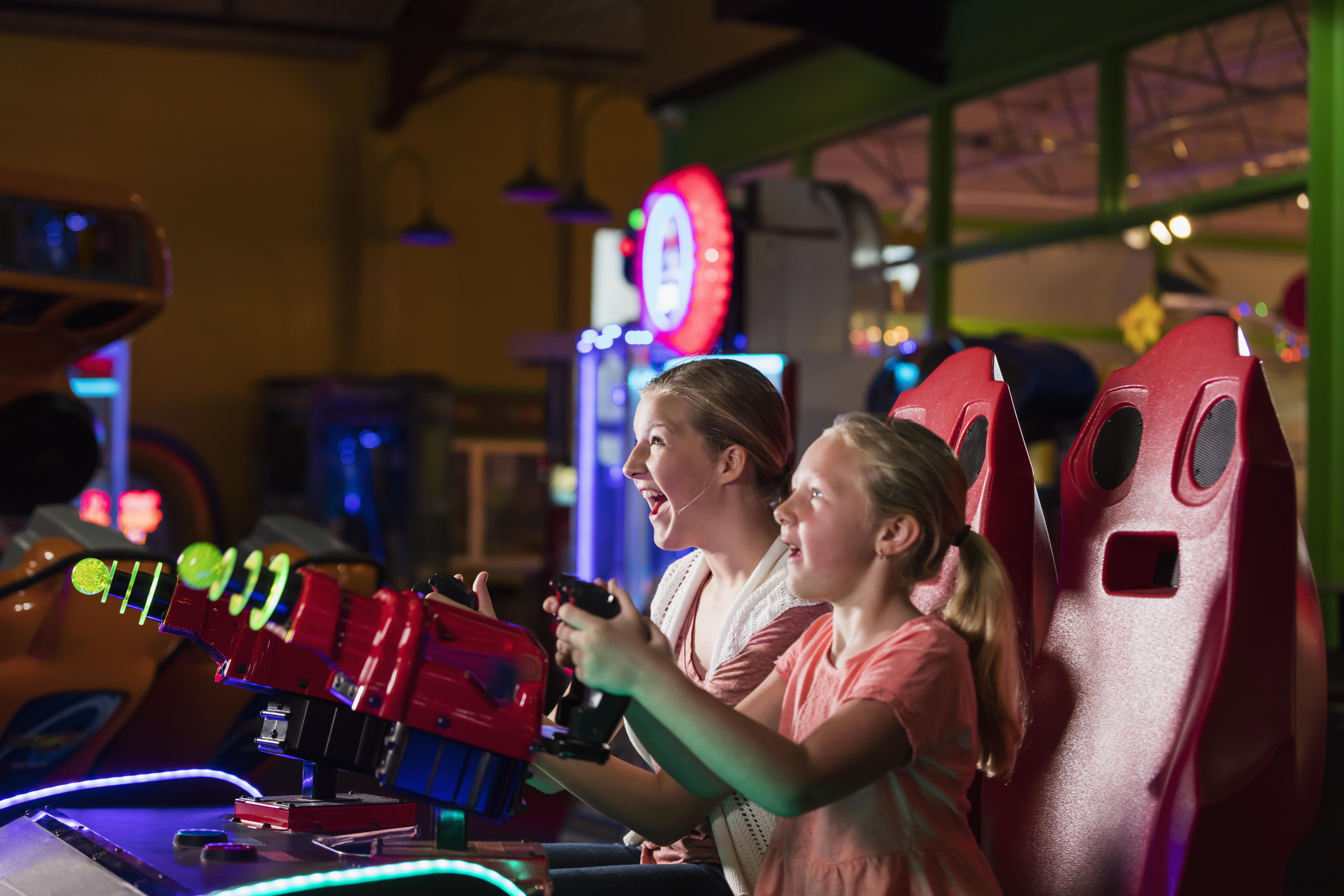 Image of a mother and daughter happily playing an arcade game together.