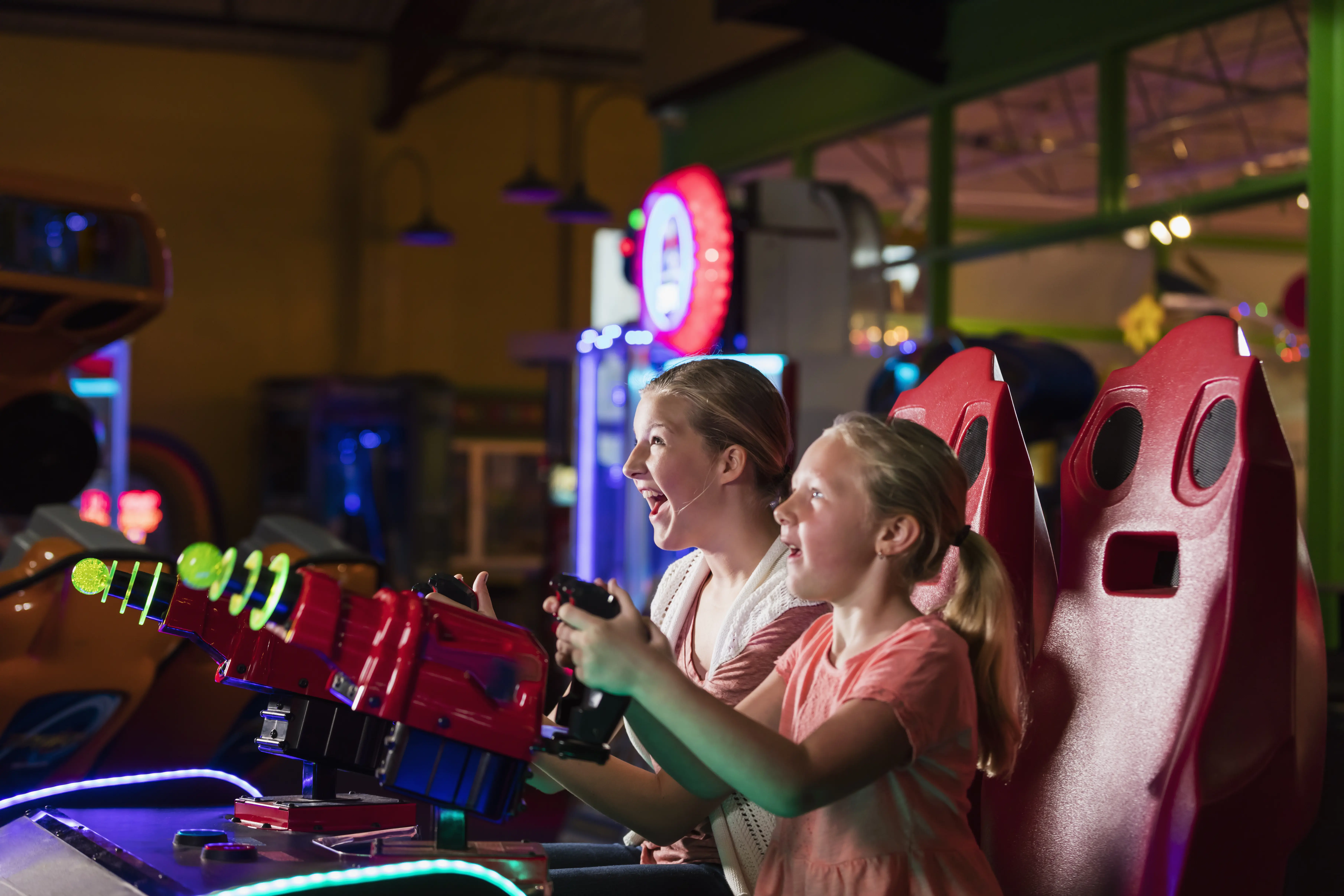 Image of a mother and daughter happily playing an arcade game together.