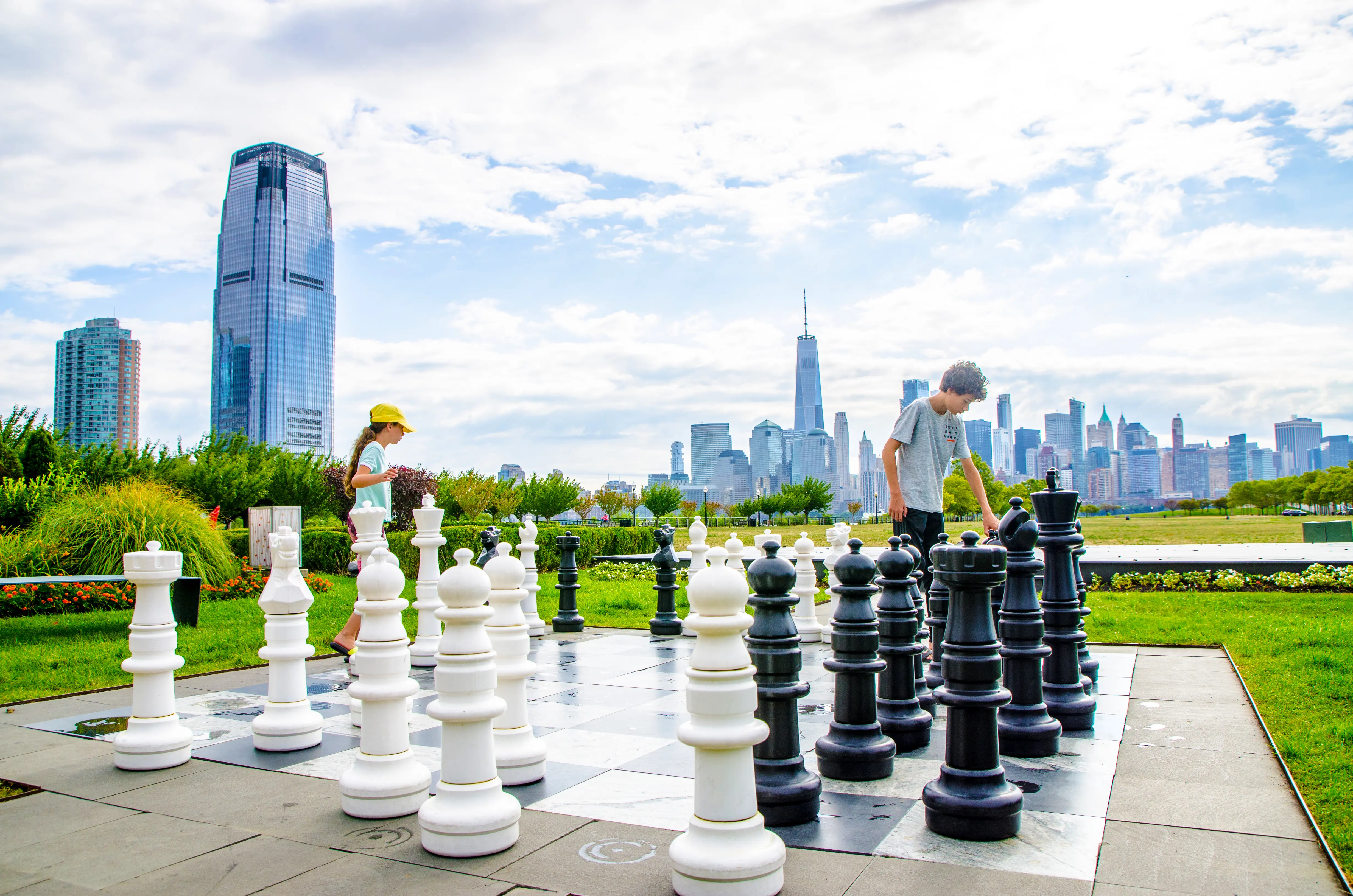 Two teens playing chess outside on a giant chess set in Liberty State Park
