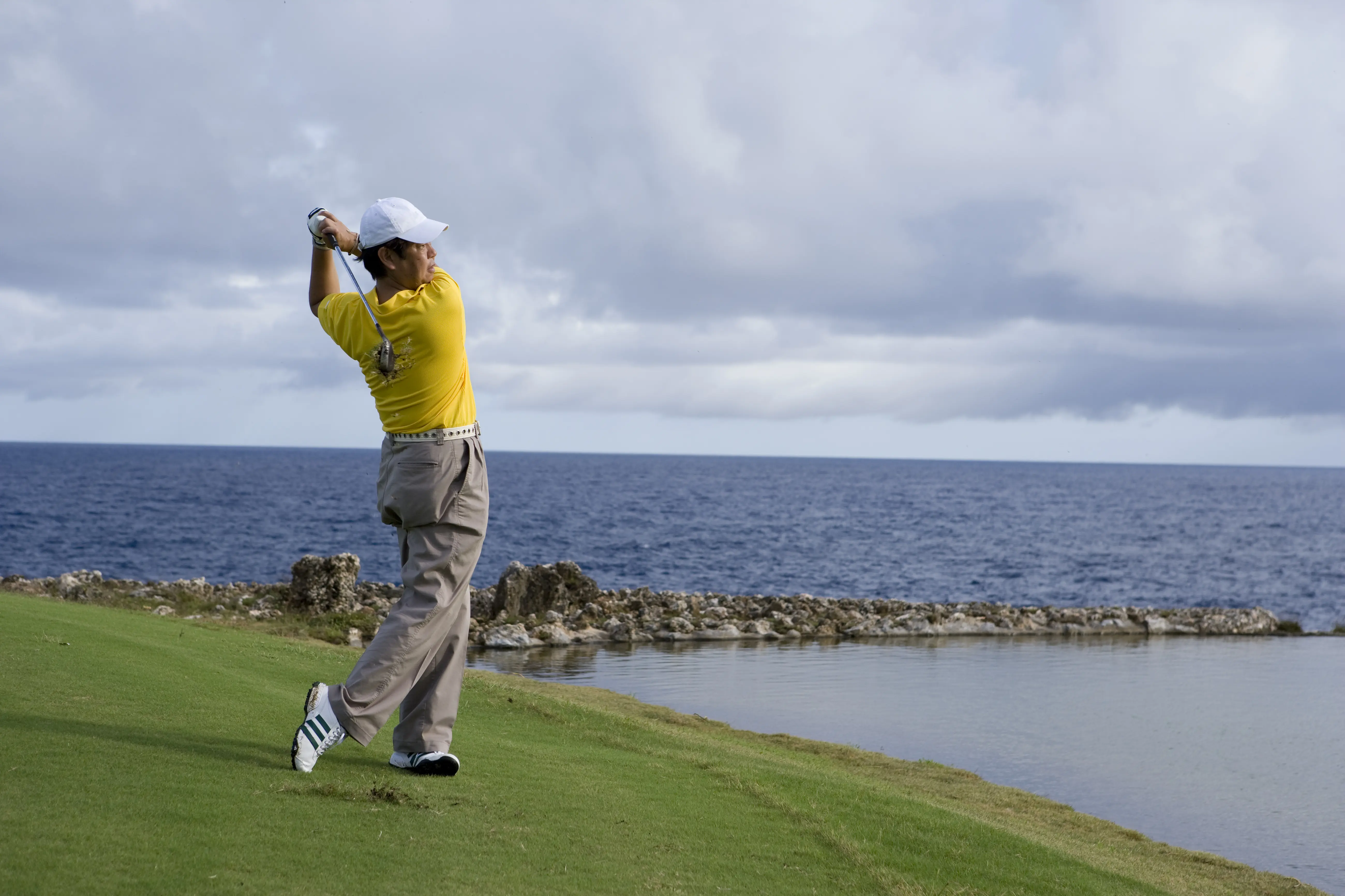 Image of a man golfing on an oceanside course.
