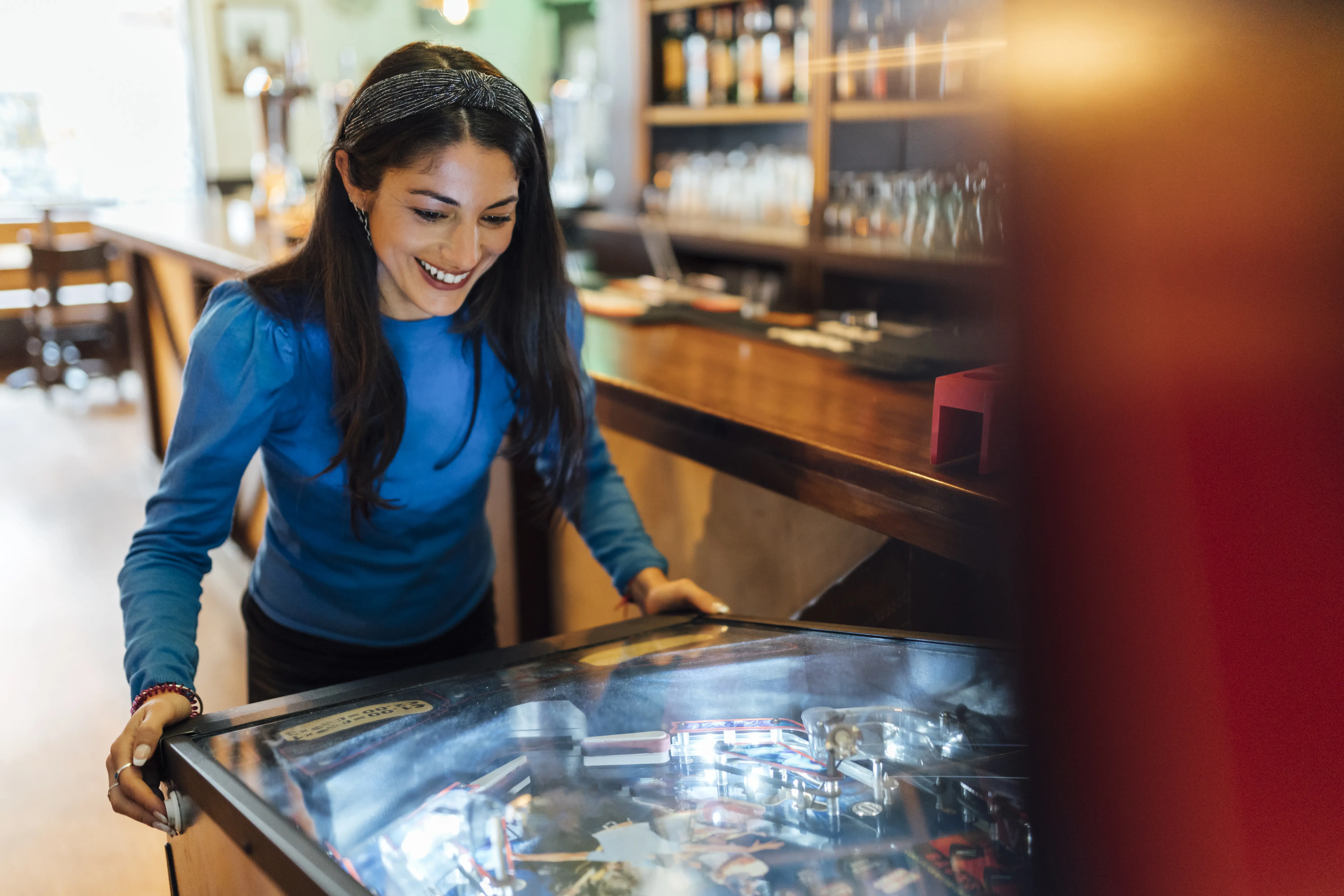 Photo of a woman playing a game of pinball.