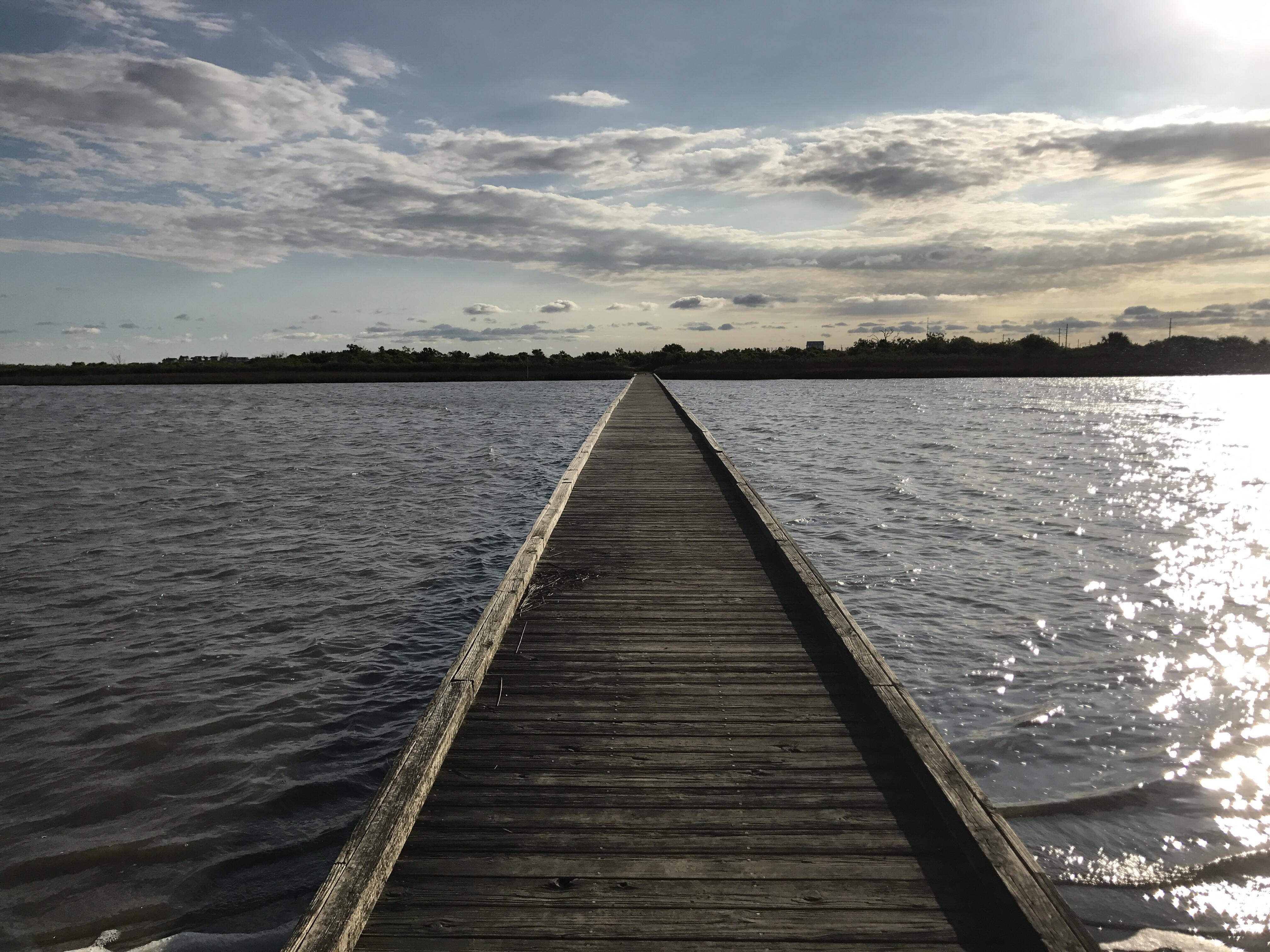 Outdoor image of a wooden boat dock going out over the water.