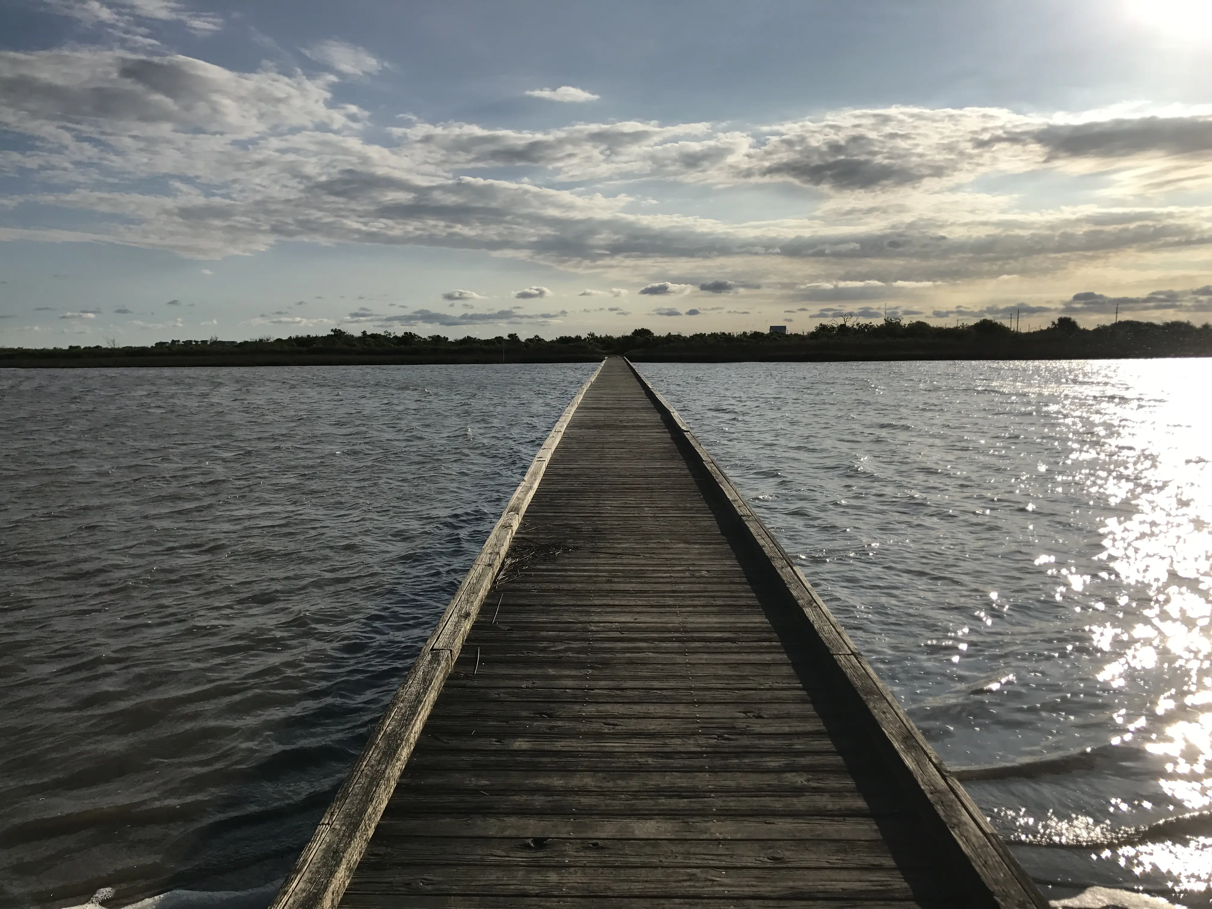Outdoor image of a wooden boat dock going out over the water.