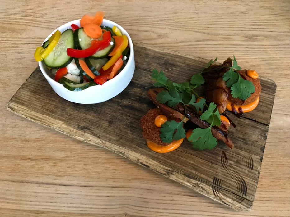 Wood serving plank topped with pickled veggies and pork belly balls from SMITH restaurant in Winnipeg, Manitoba.