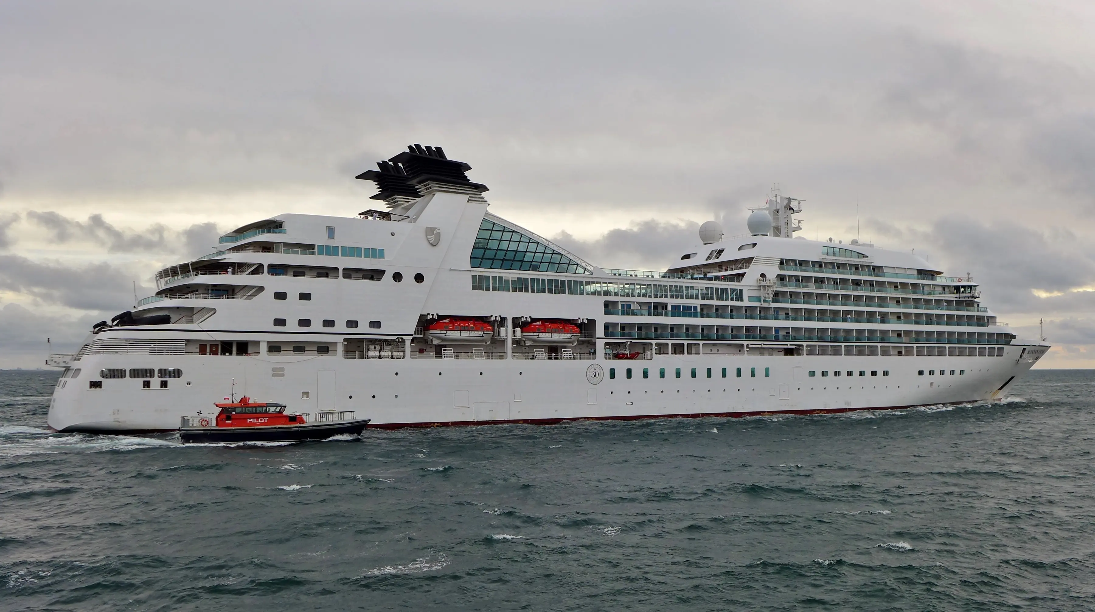 Image of the Seabourn Sojourn sailing with a pilot boat guiding it out.