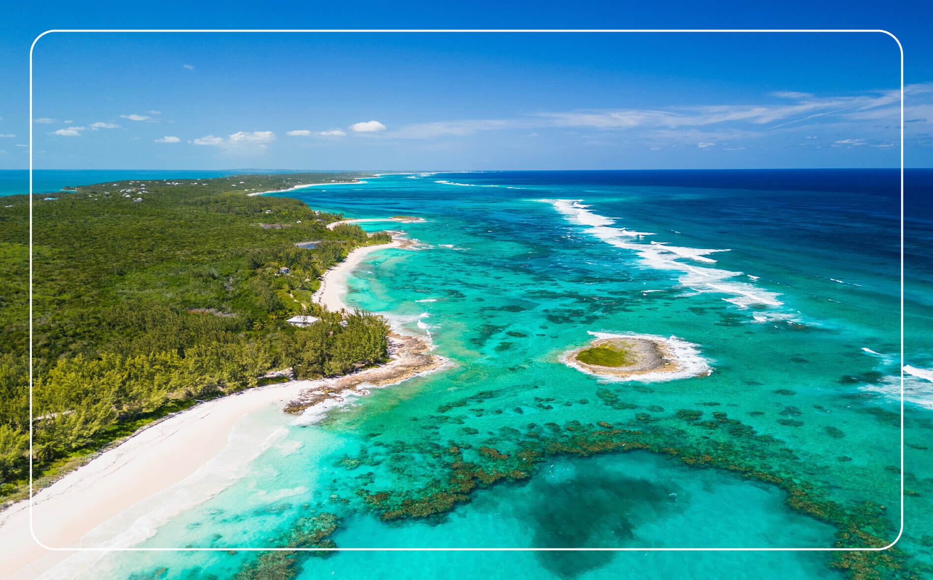 Aerial view of The Bahamas coastline showing vivid turquoise ocean waters meeting lush green land.