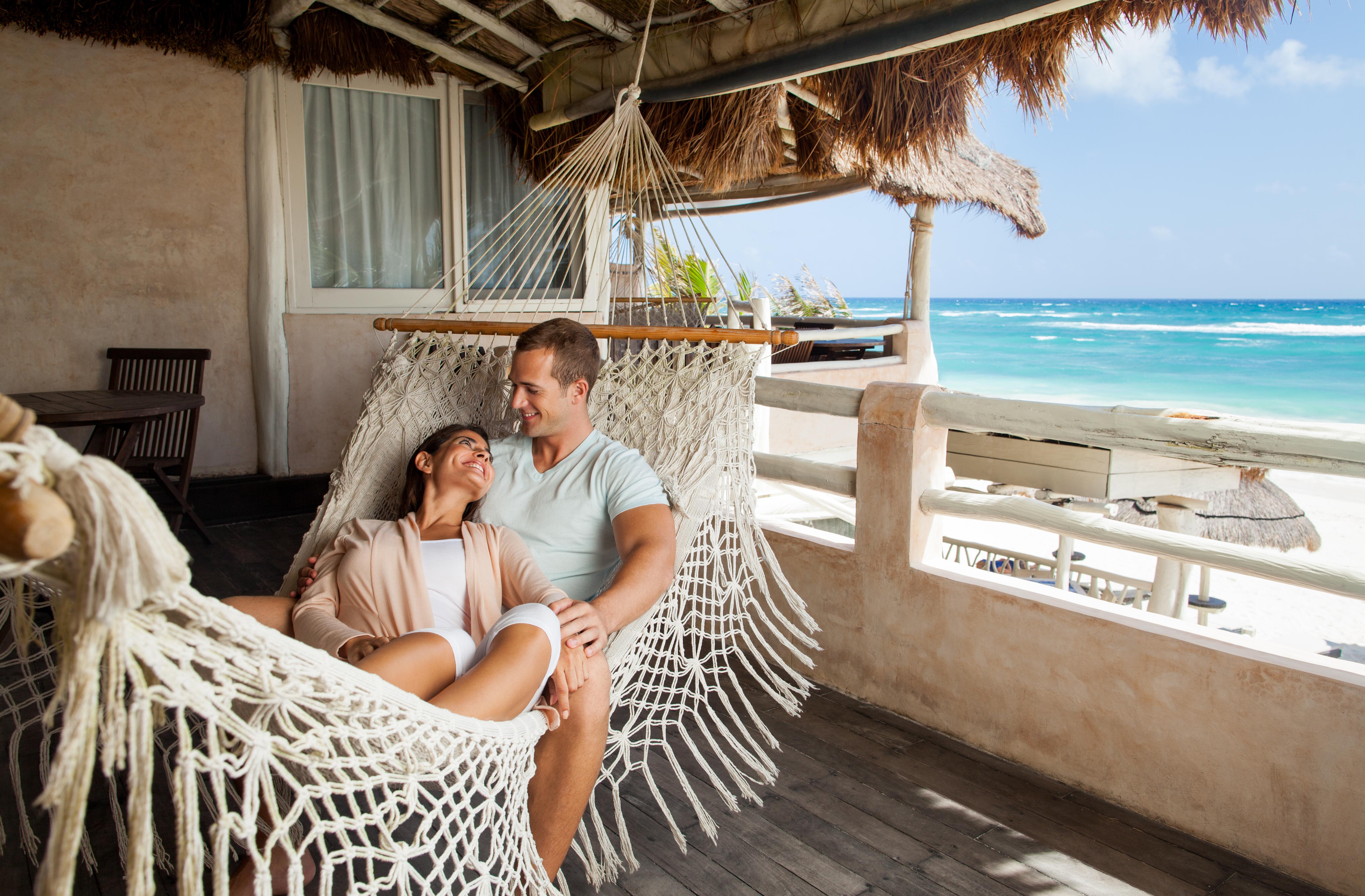 Image of a happy couple in a hammock together, in a tropical setting.