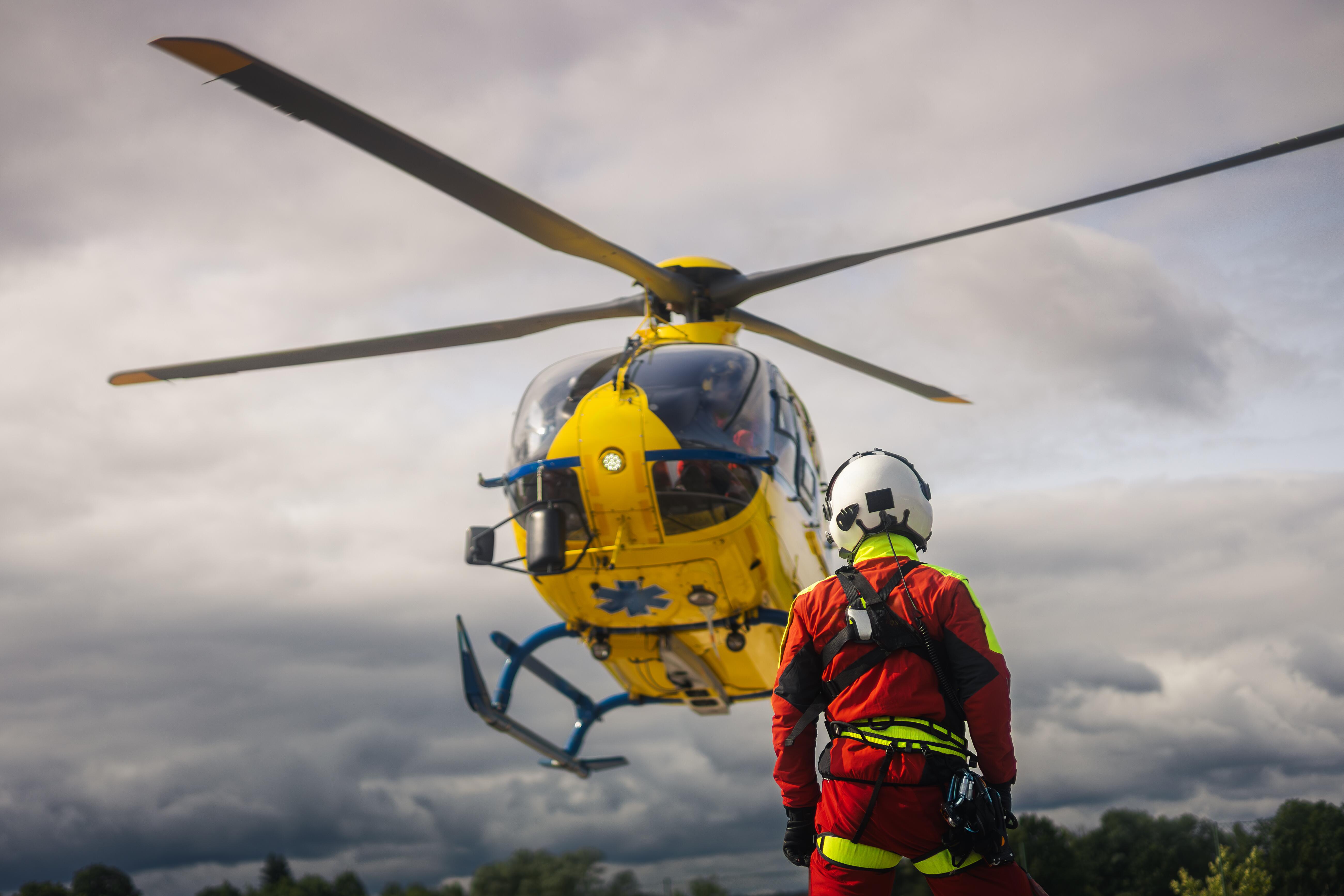 Image of a paramedic approaching a landing medical helicopter.