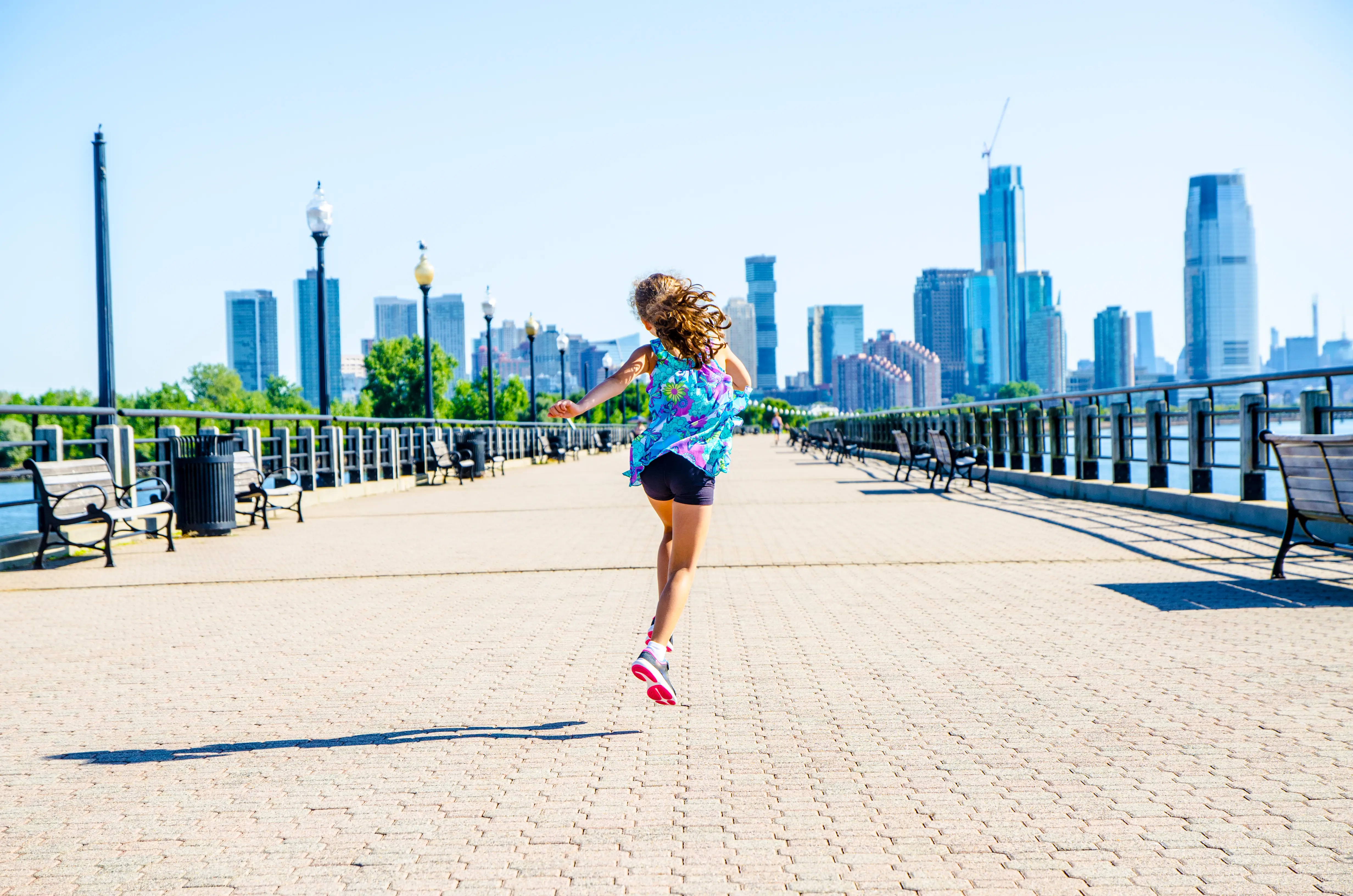 Young girl skipping on boardwalk at Liberty State Park