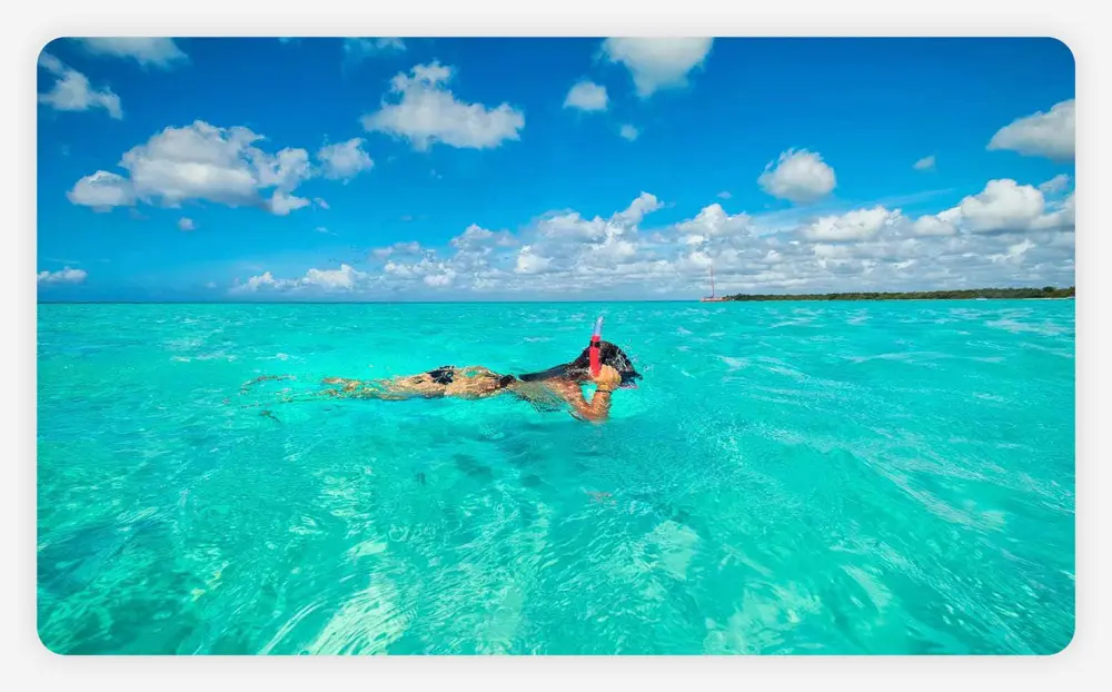 A young woman snorkeling in blue Caribbean waters.
