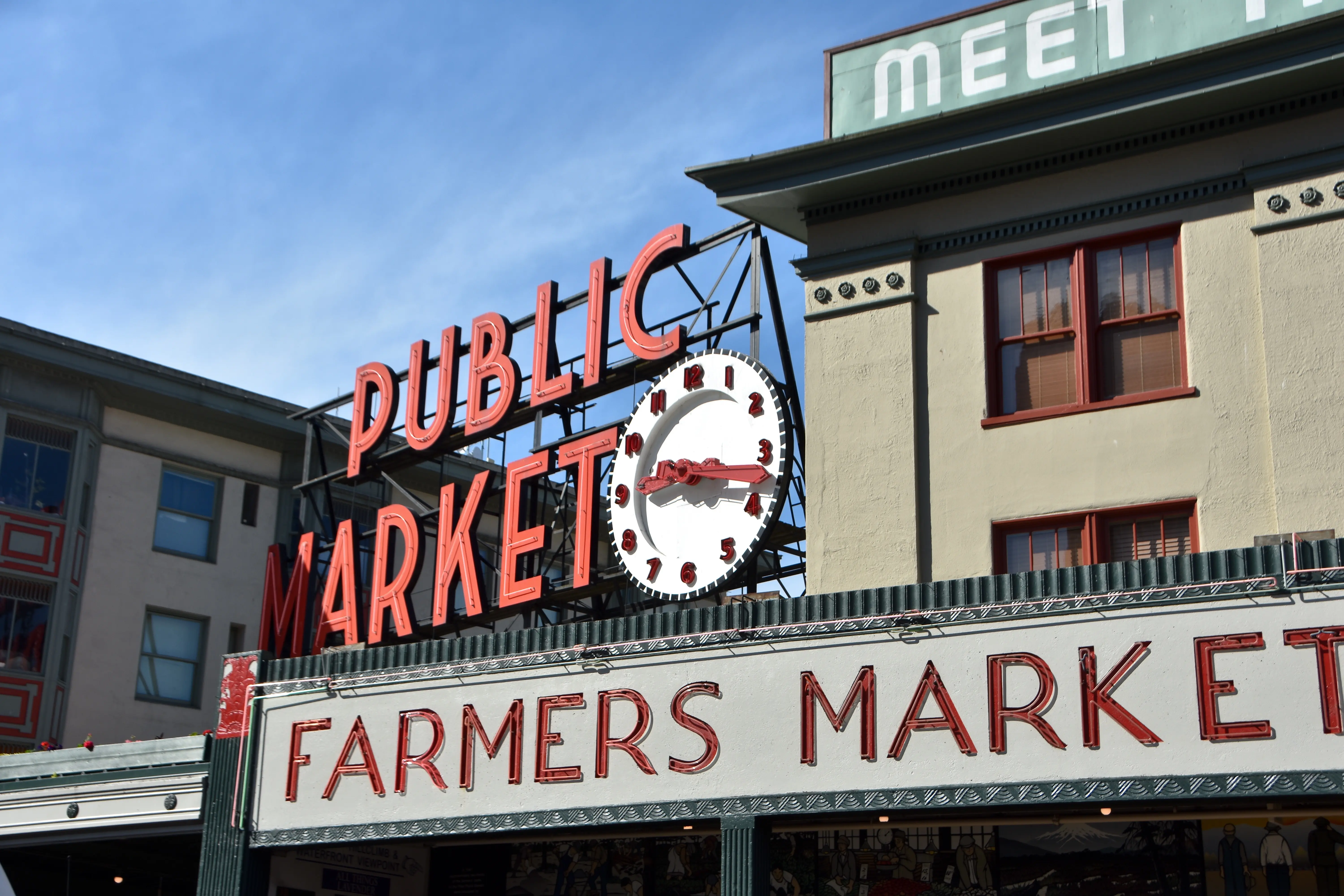 The red Public Market sign above a sign for the farmers market at Pike Place Market in Seattle, Washington.
