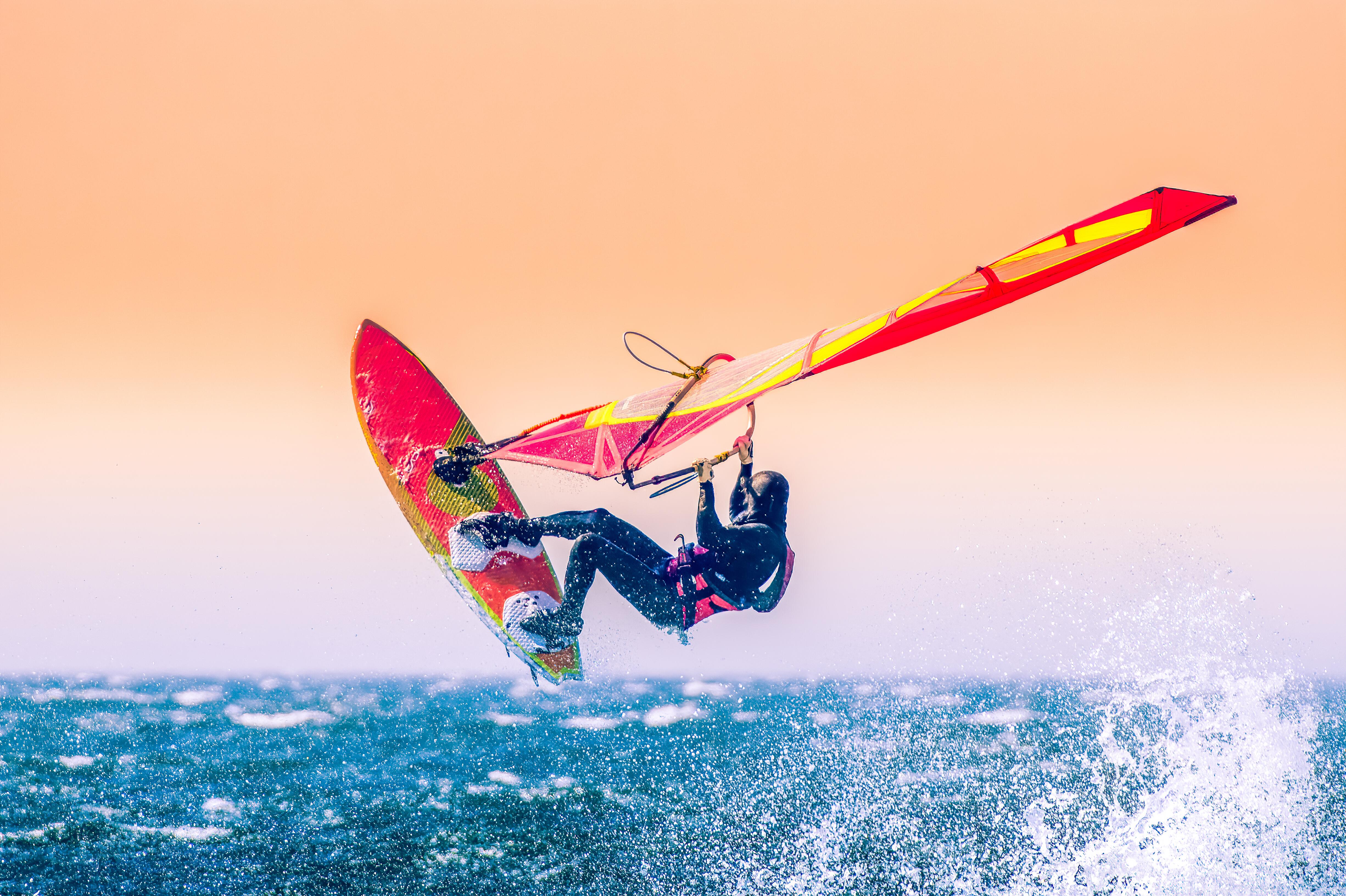 Outdoor picture of a person windsurfing on the ocean as the sun sets.