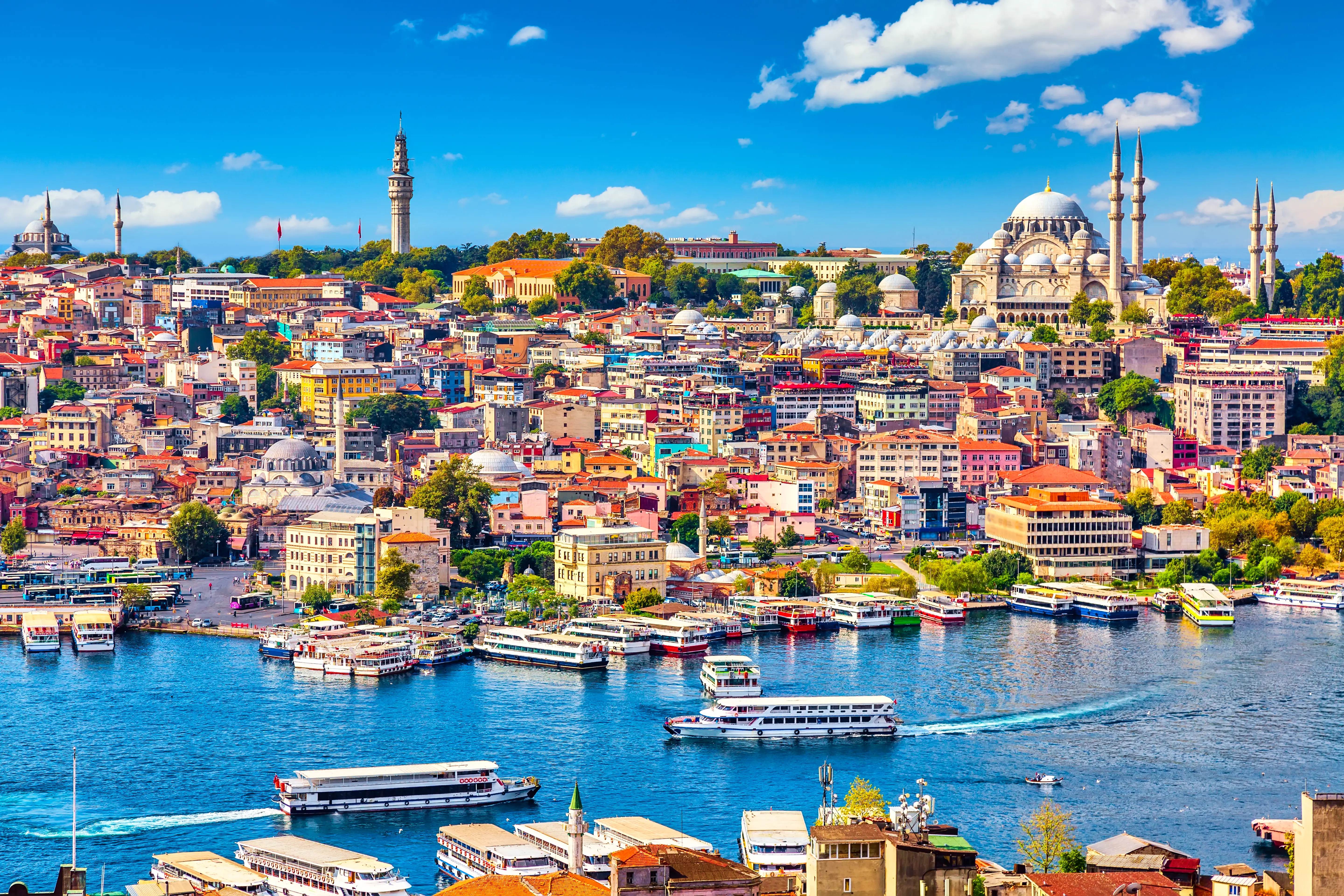 Touristic sightseeing ships in Golden Horn bay of Istanbul and mosque with Sultanahmet district against blue sky and clouds