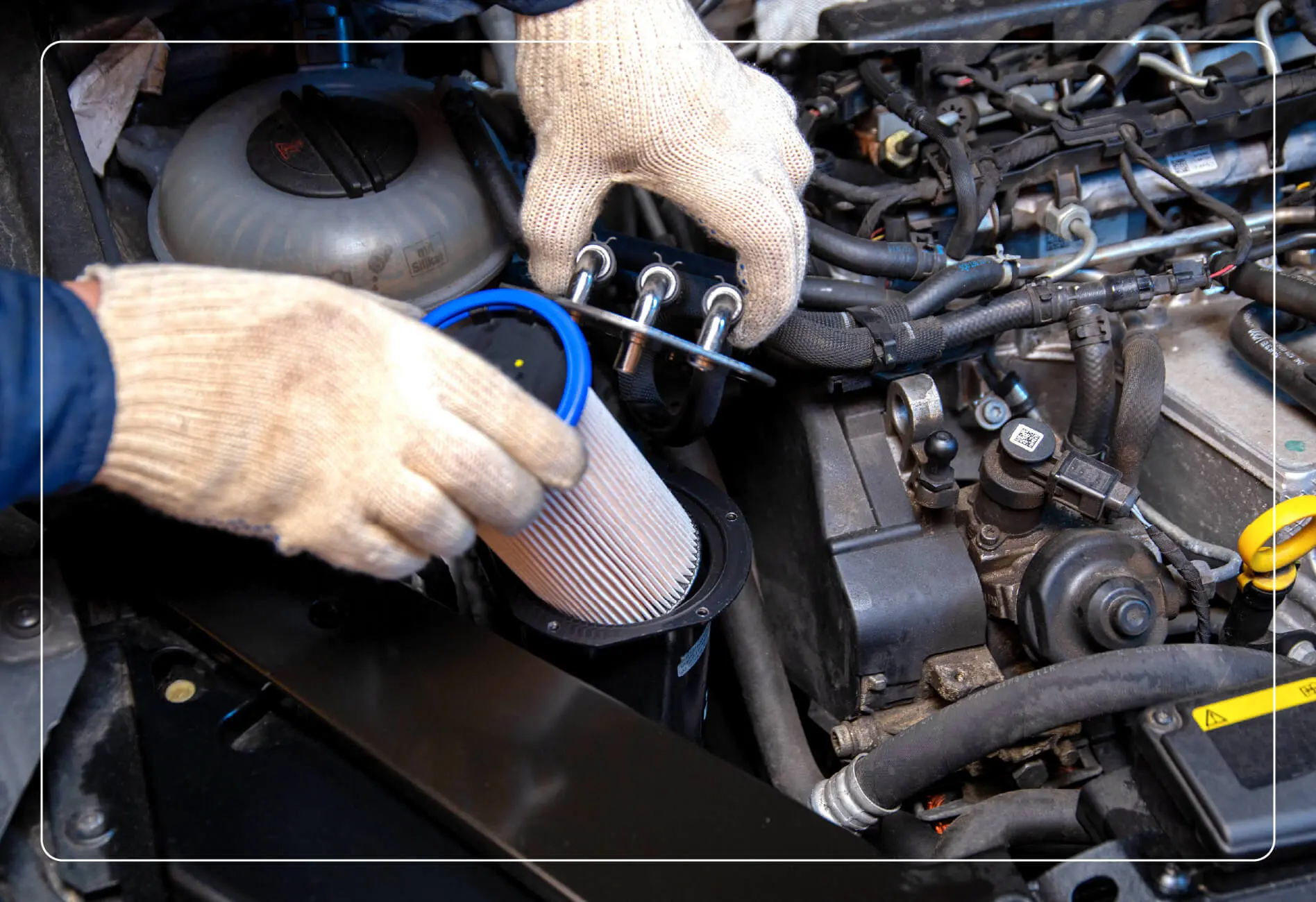 A person with gloves on trying to replace a car fuel filter.