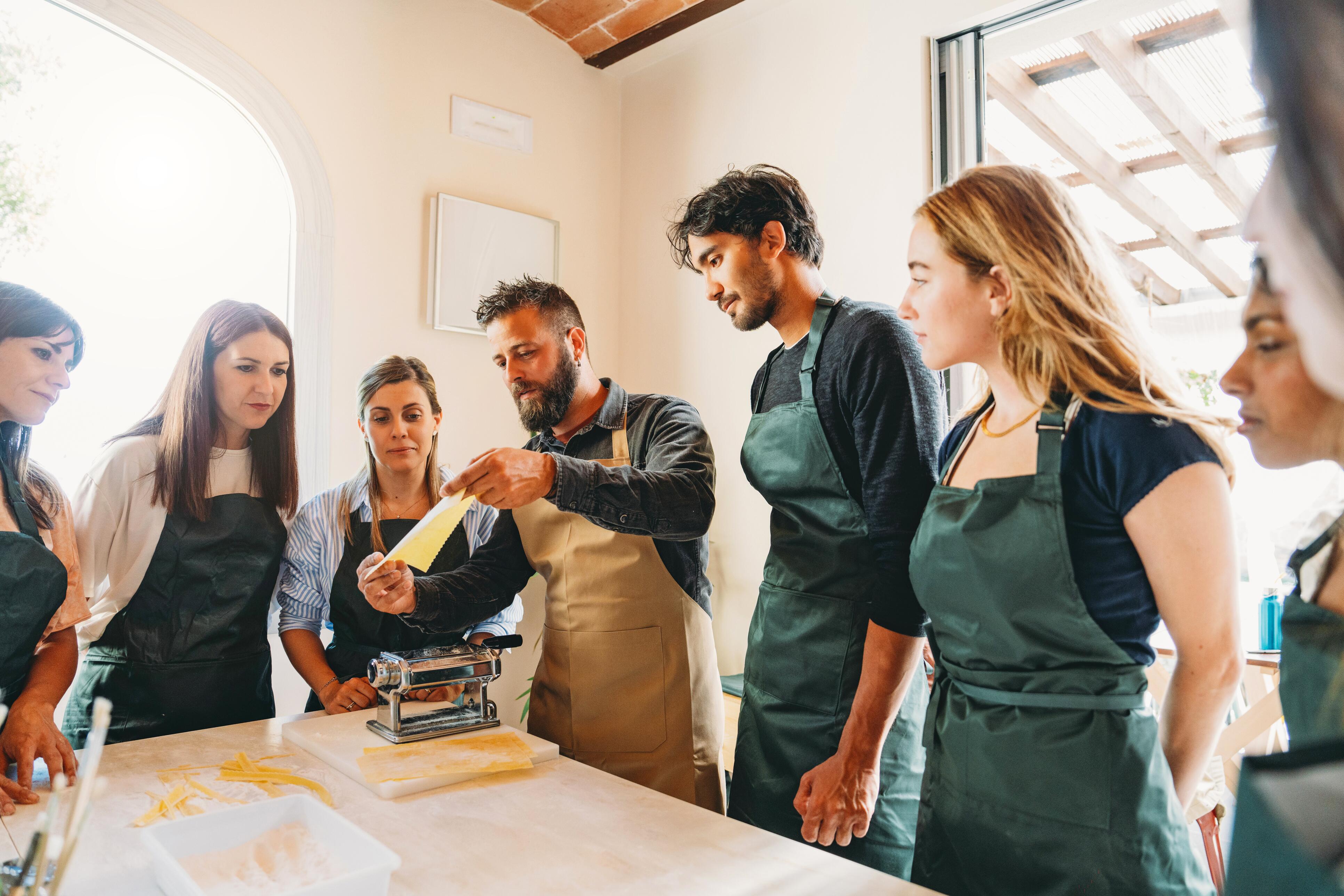 Chef demonstrating to students how to make pasta during a cooking class