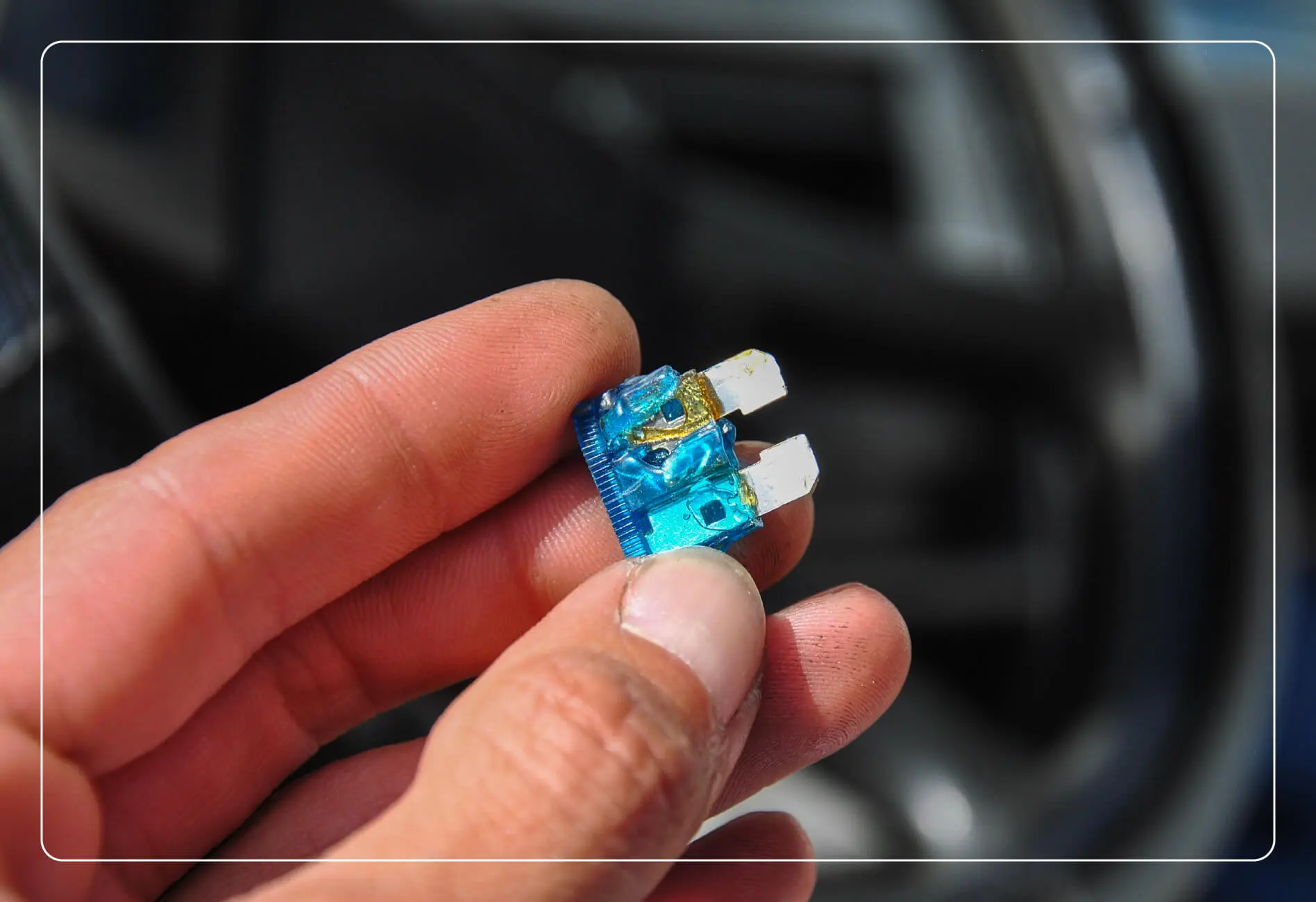 A hand holding a car fuse.