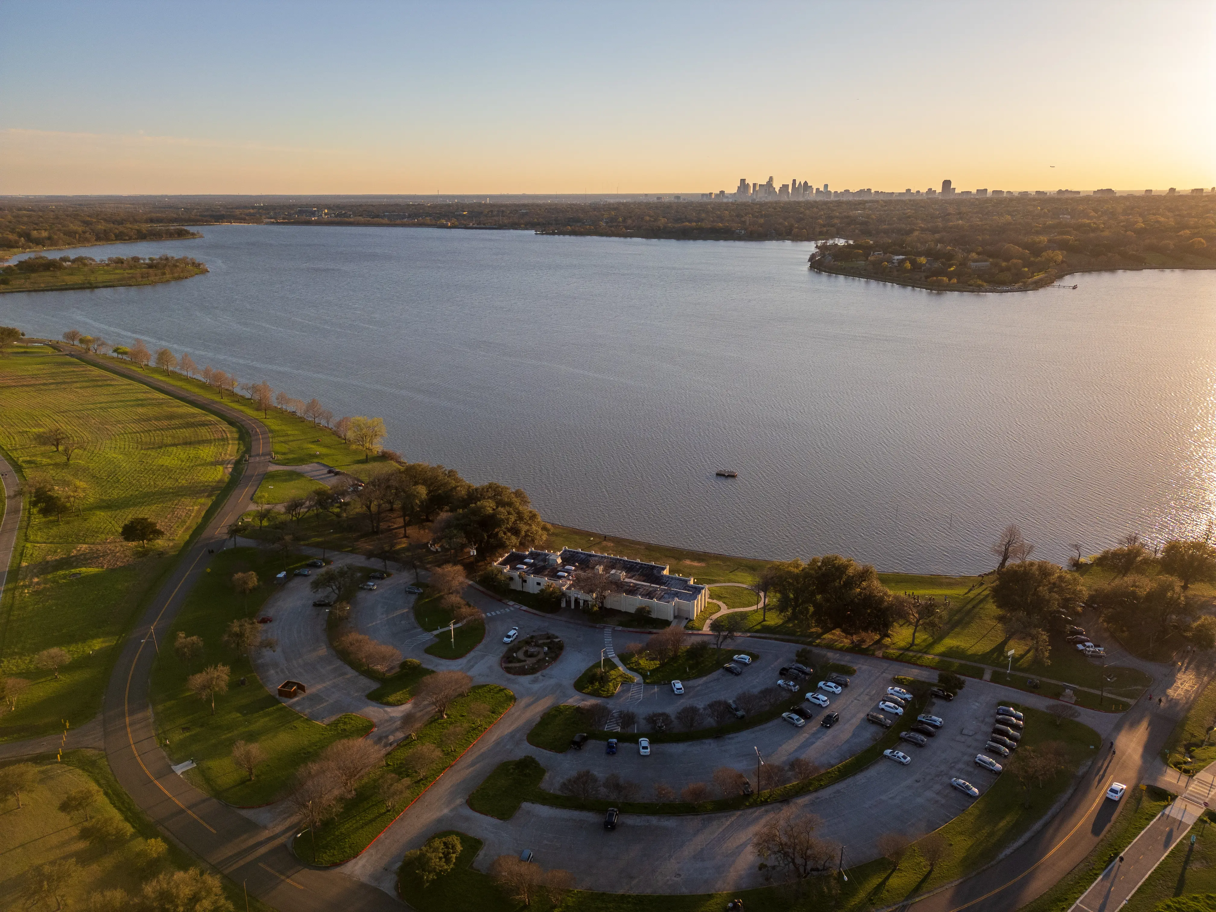 Aerial image of the Bath House Cultural Center at White Rock Lake, with the Dallas skyline visible in the background.