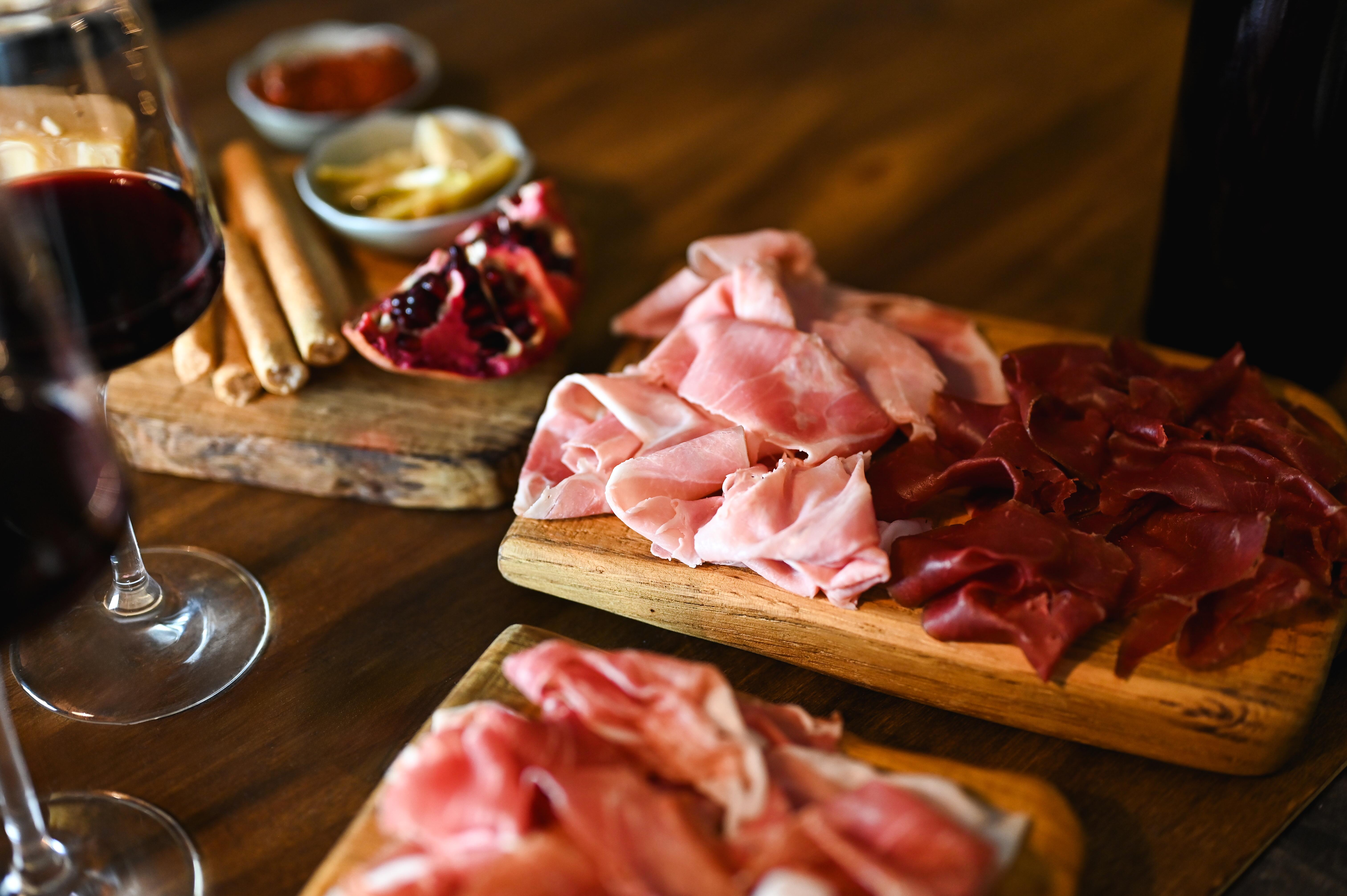 Charcuterie board full of cold cuts, beef bresaola, with red wine on a table