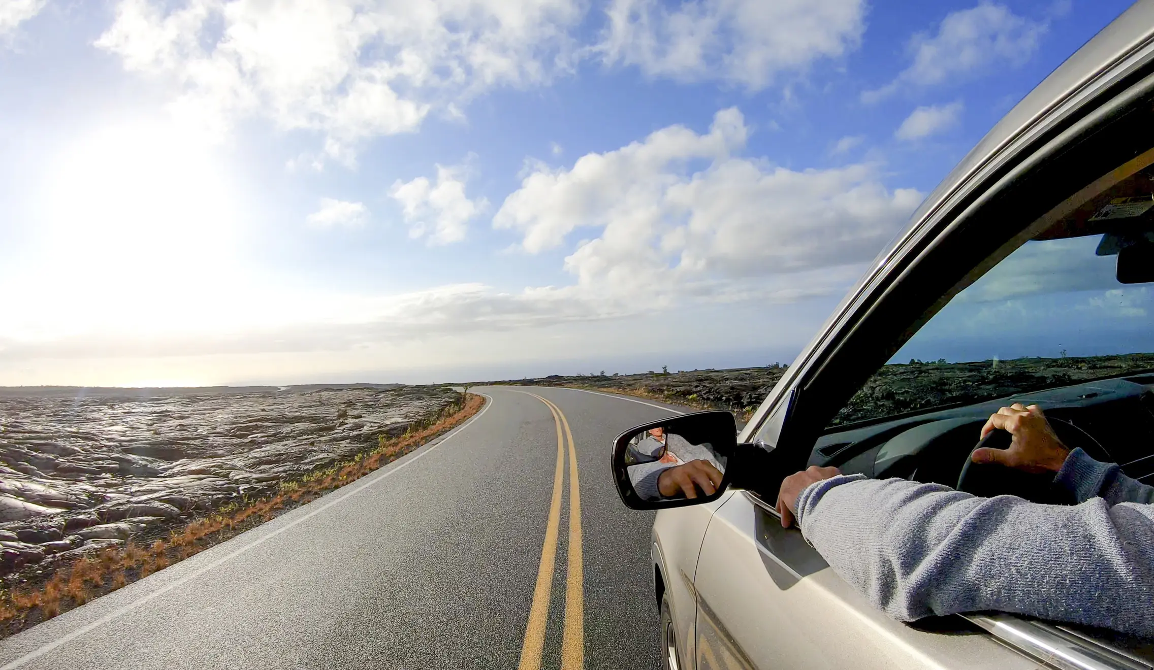 Car driving on the Chain of Craters Road with views of lava in Hawaii Volcanoes National Park.