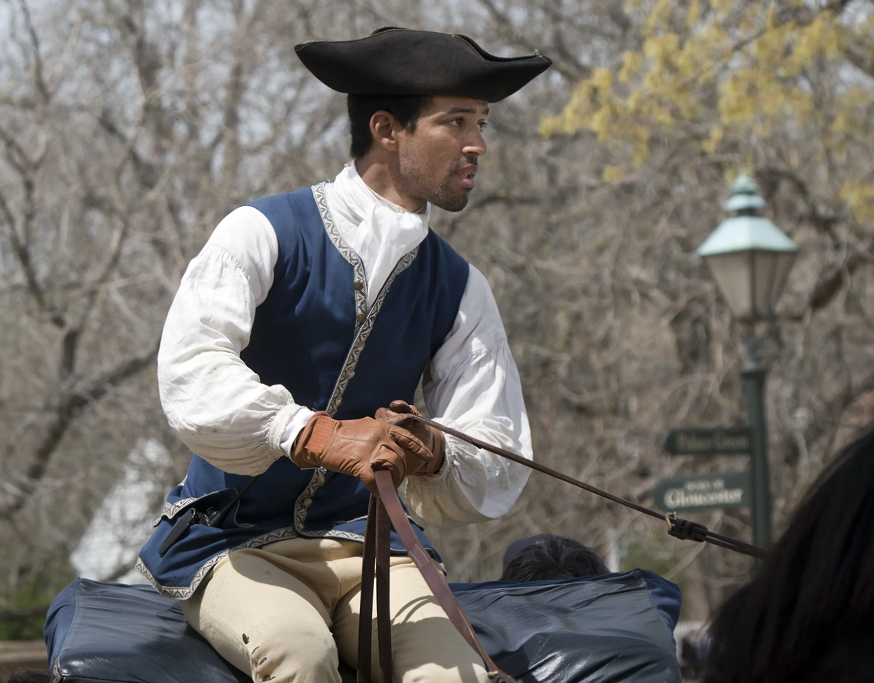 Image of a young man acting as a carriage horse driver/rider in Colonial Williamsburg.