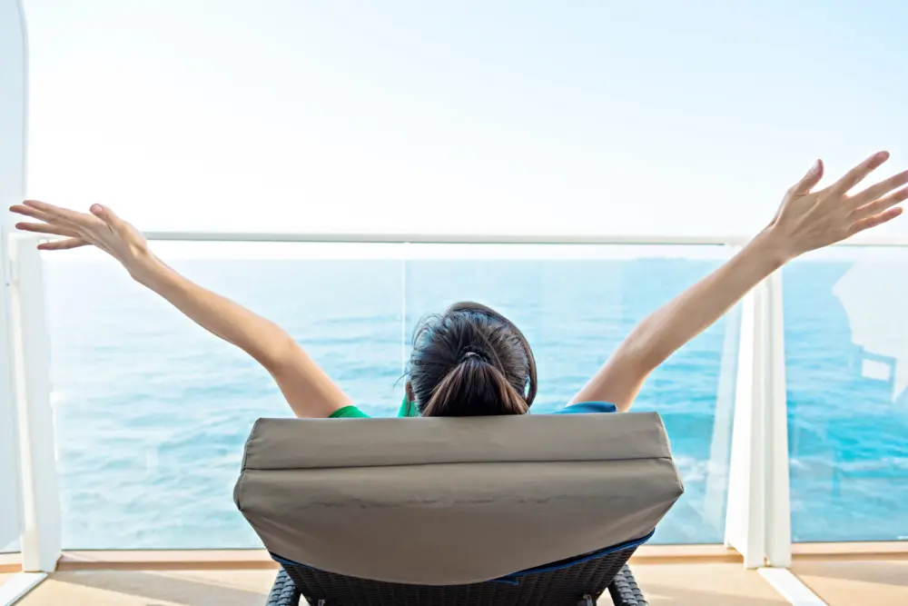 Lady with open arms sunning on a cruise ship balcony