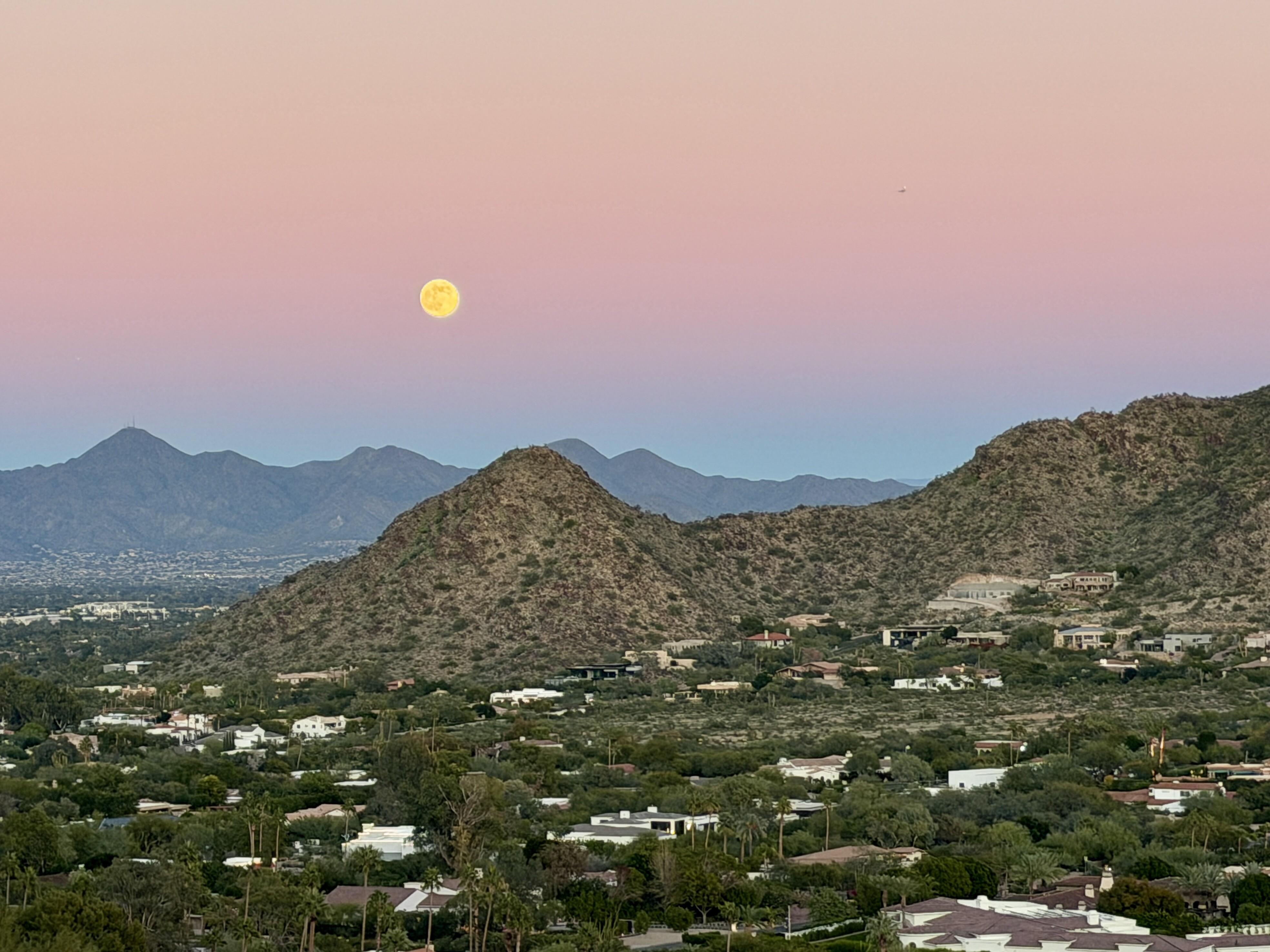 A bird's-eye-view of Scottsdale with houses and streets stretching out to mountains that stand over the city.
