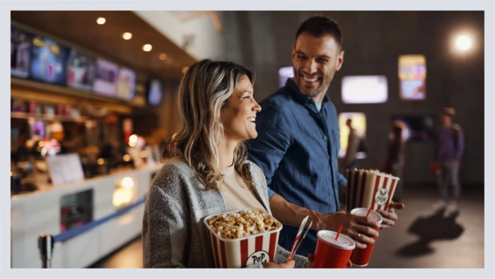  A couple holds popcorn and drinks at the movie theater.