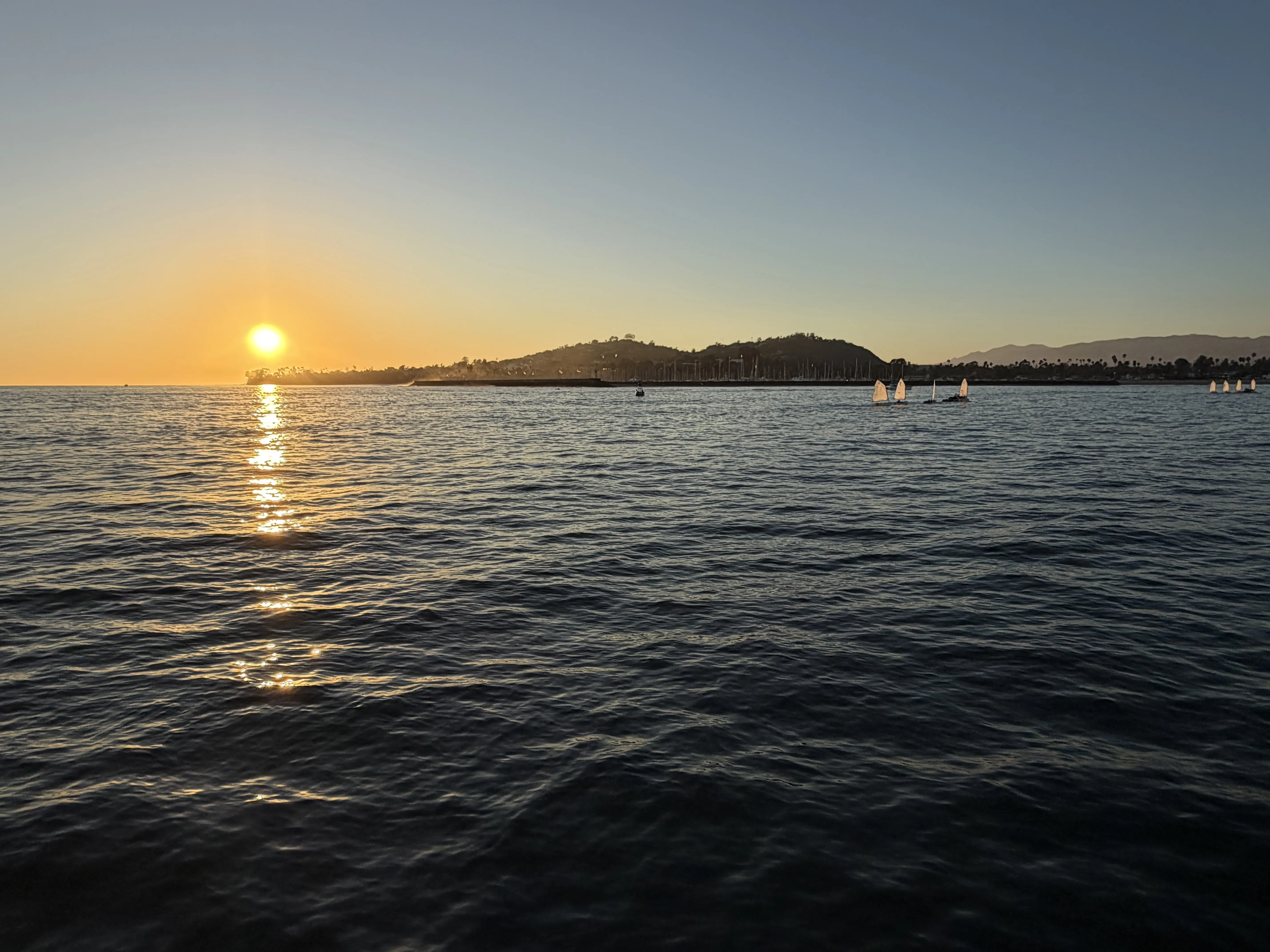 A view of the sun setting behind Santa Ynez Mountains in Santa Barbara from a sail boat.