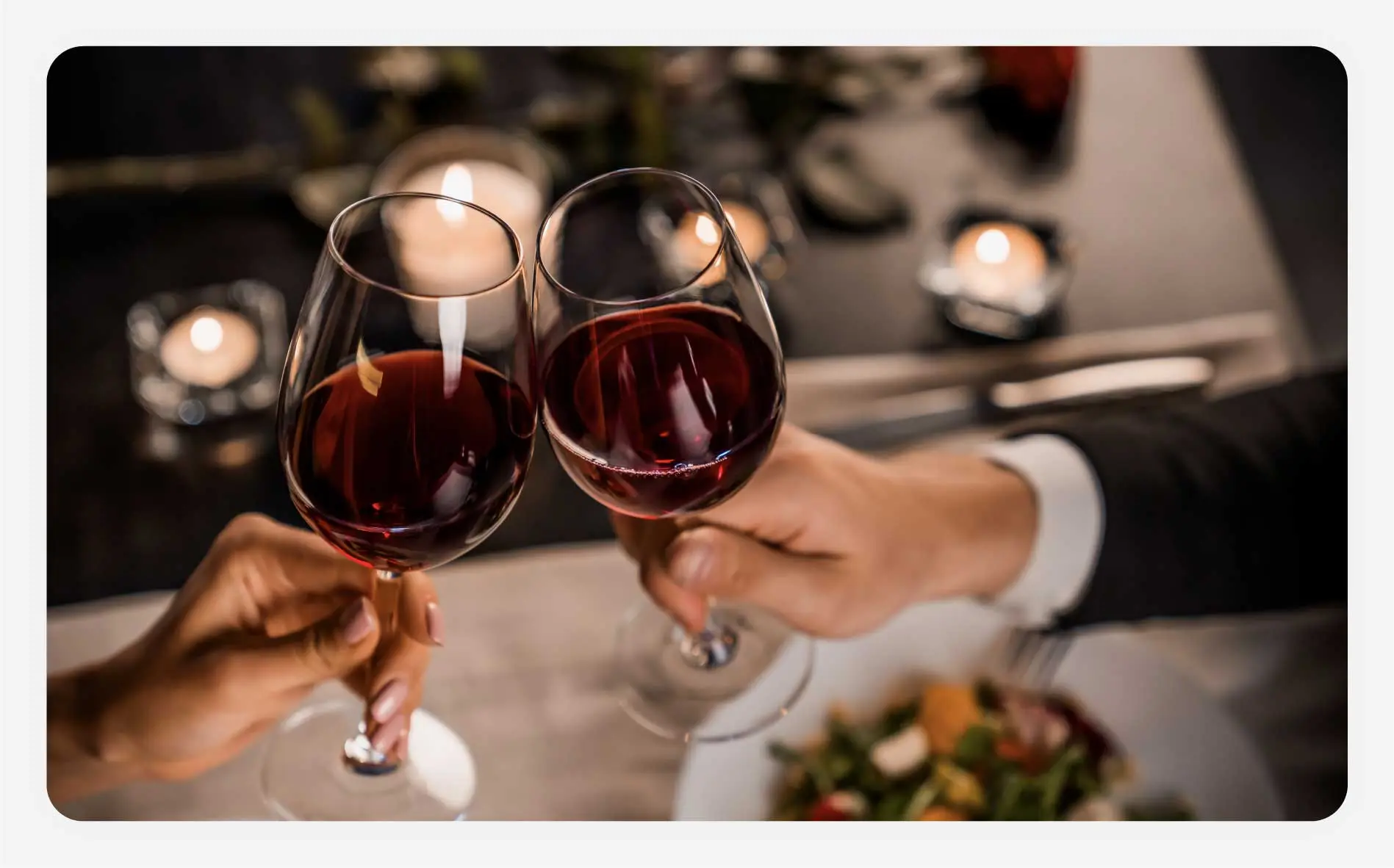 A couple clinking their red wine glasses together.