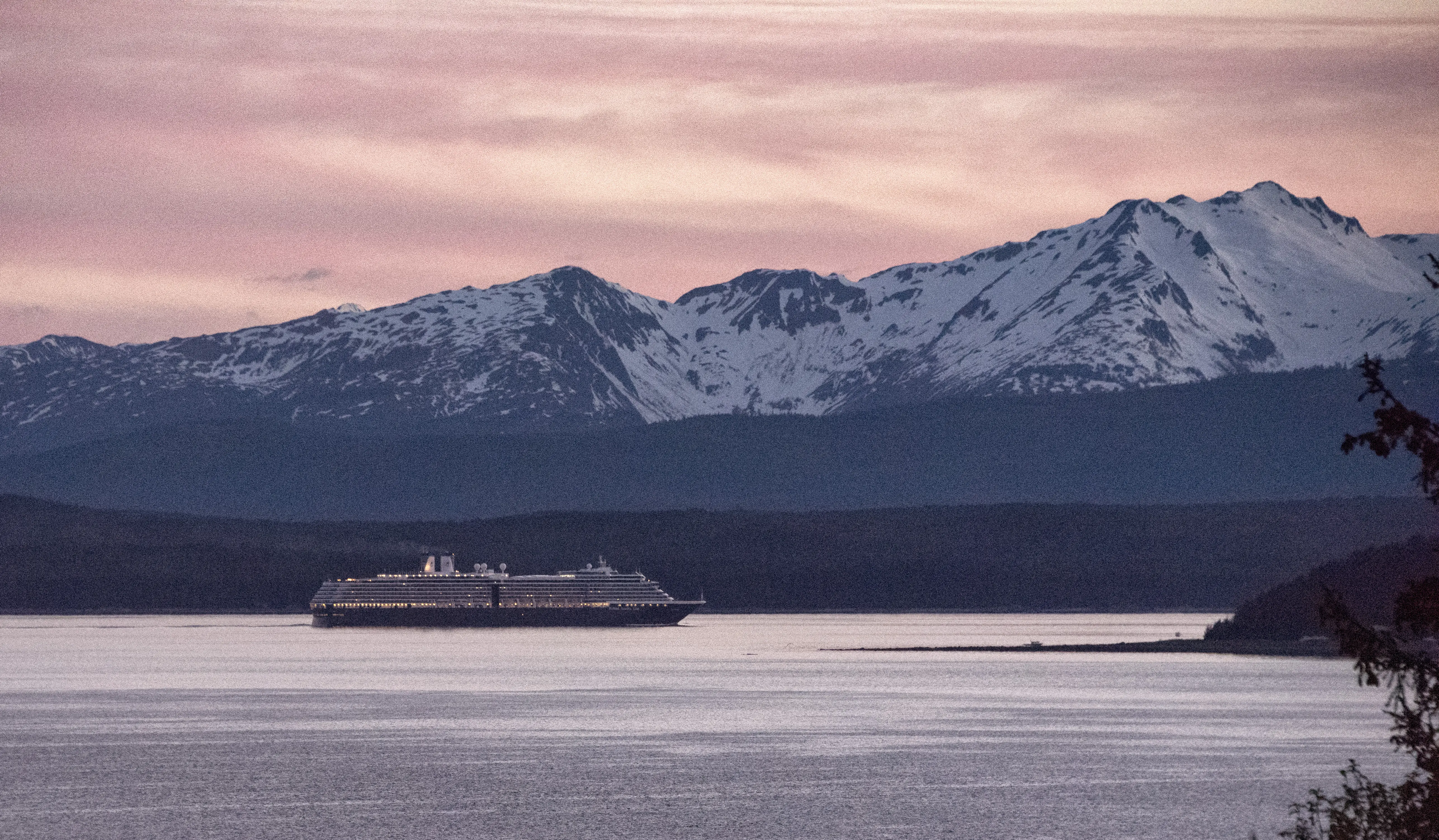 Image of a Holland America cruise ship sailing at the southern end of the Chilkat Mountain Range in Southeast Alaska at sunset.