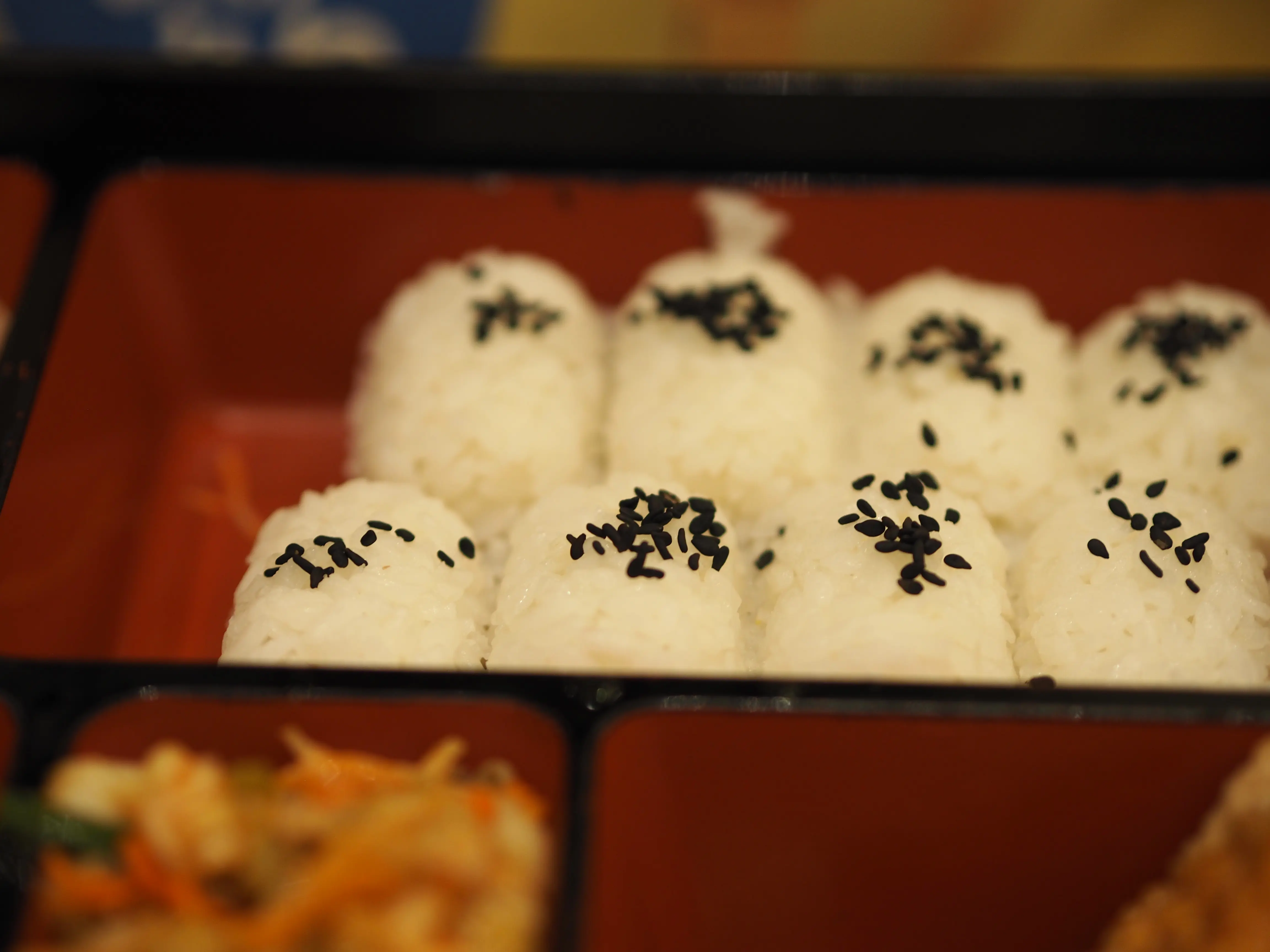 Closeup image of black sesame rice balls in a bento box style tray.