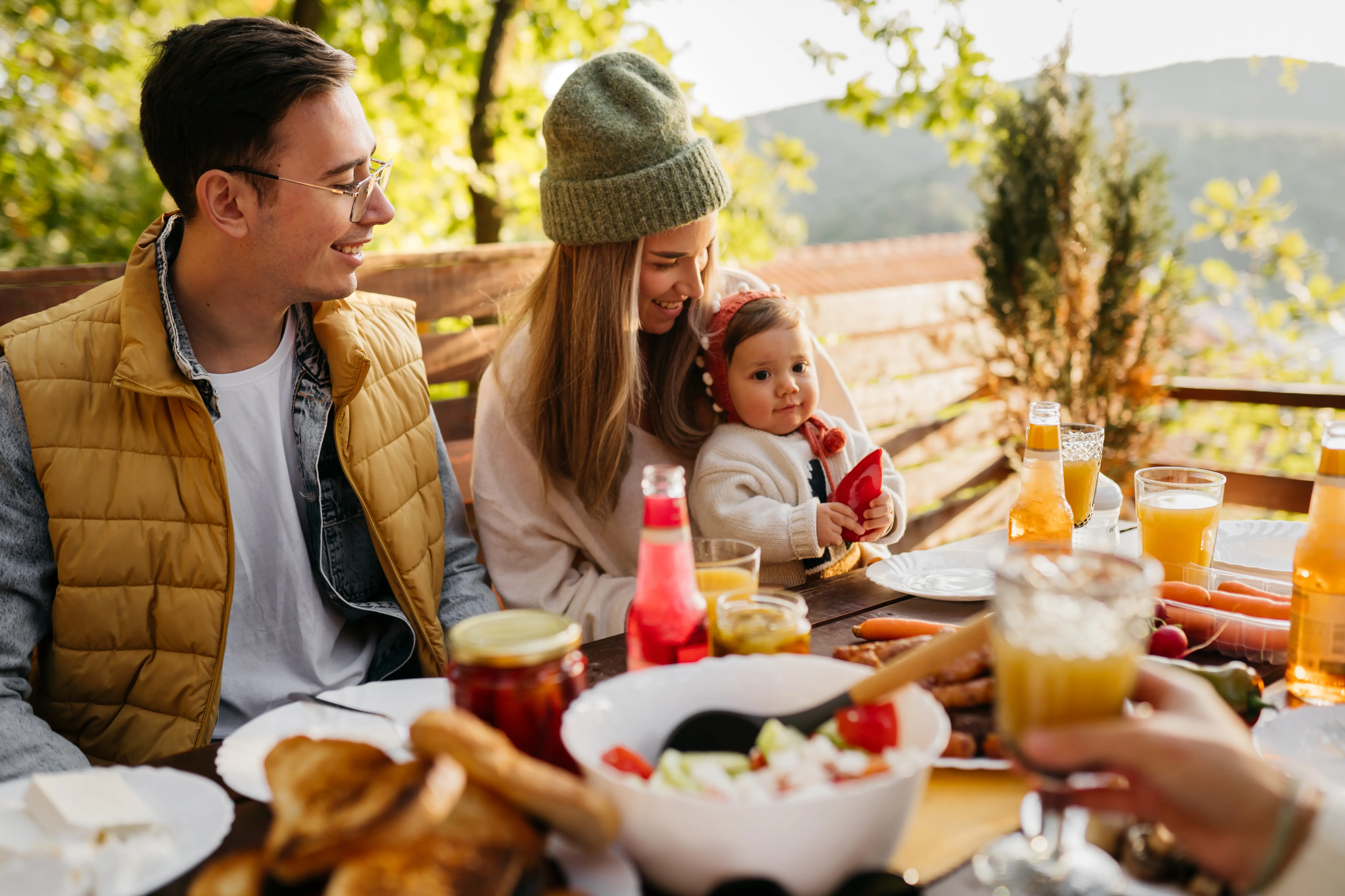 Family having lunch on a balcony in front of a wooden cabin