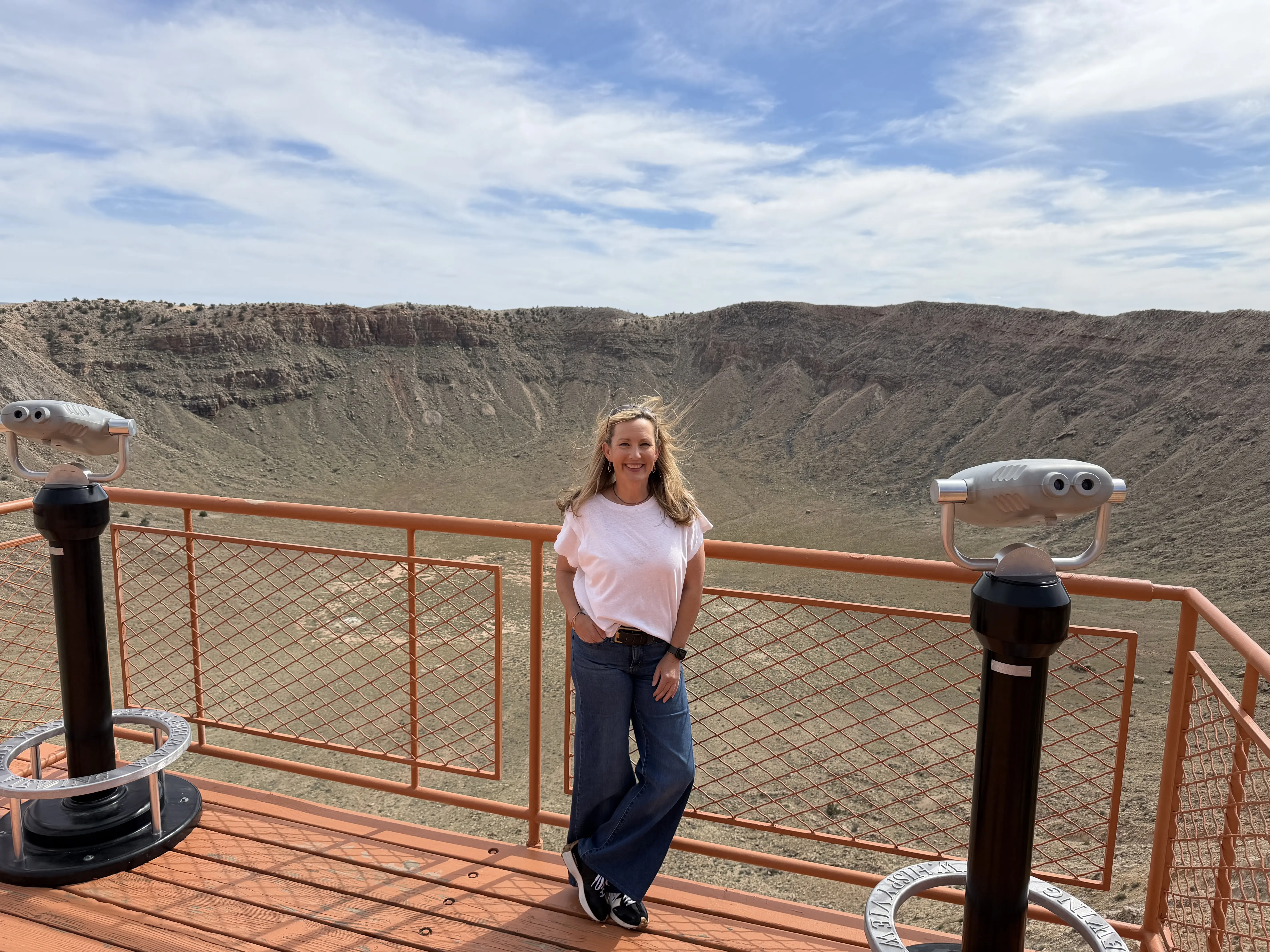 Blonde woman poses on observation deck overlooking the massive Meteor Crater in Arizona