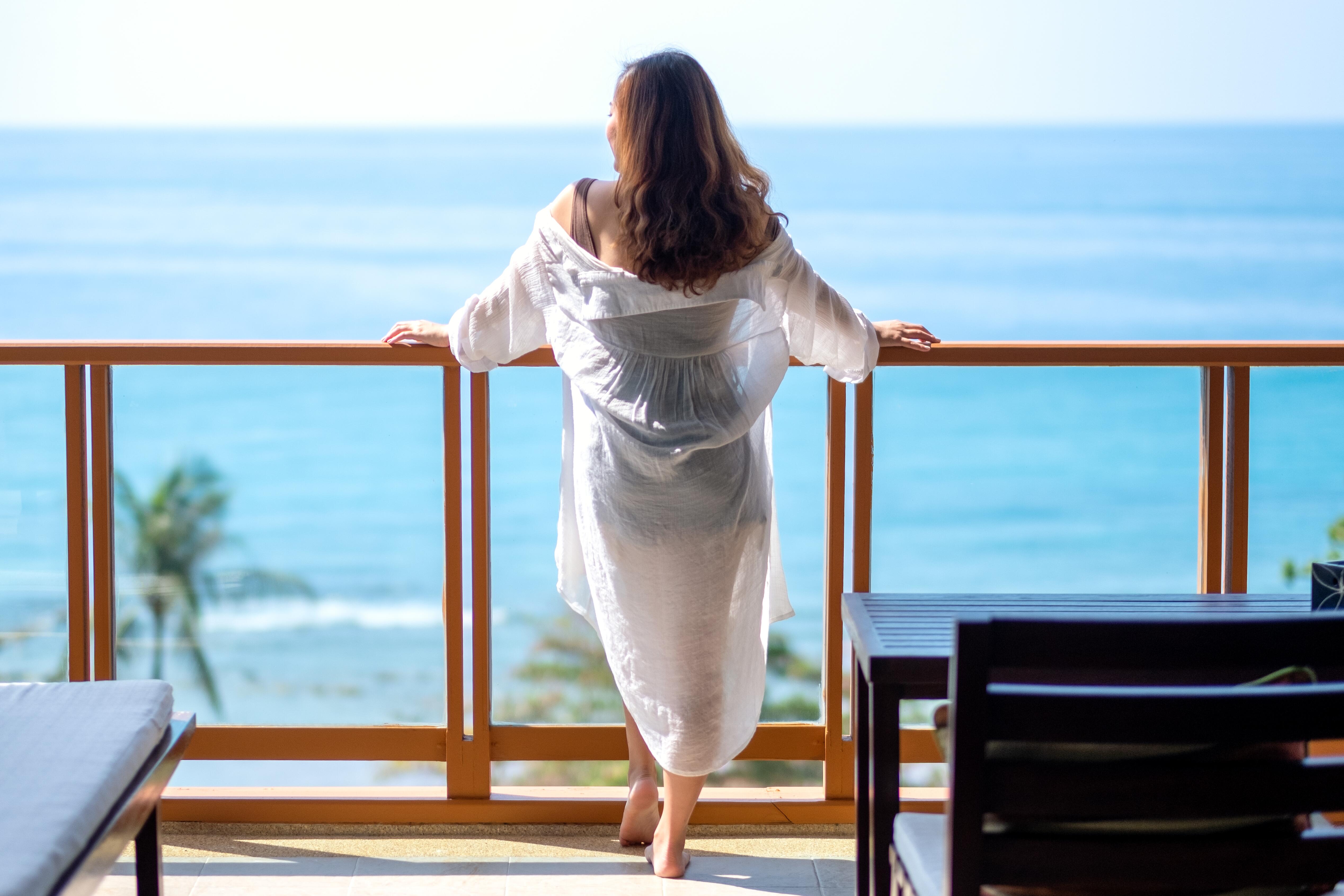 A beautiful asian woman standing and watching the sea view at balcony