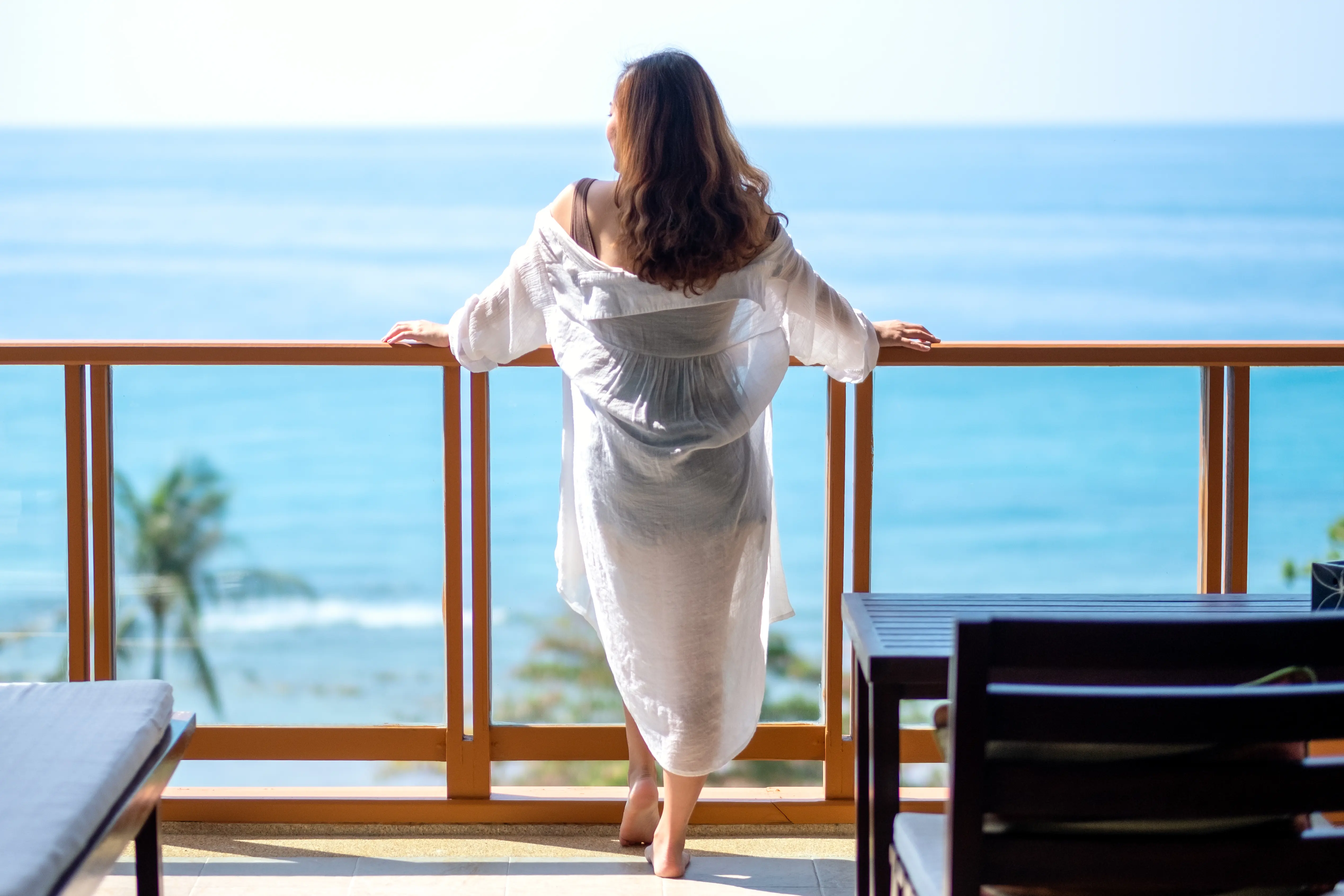 A beautiful asian woman standing and watching the sea view at balcony